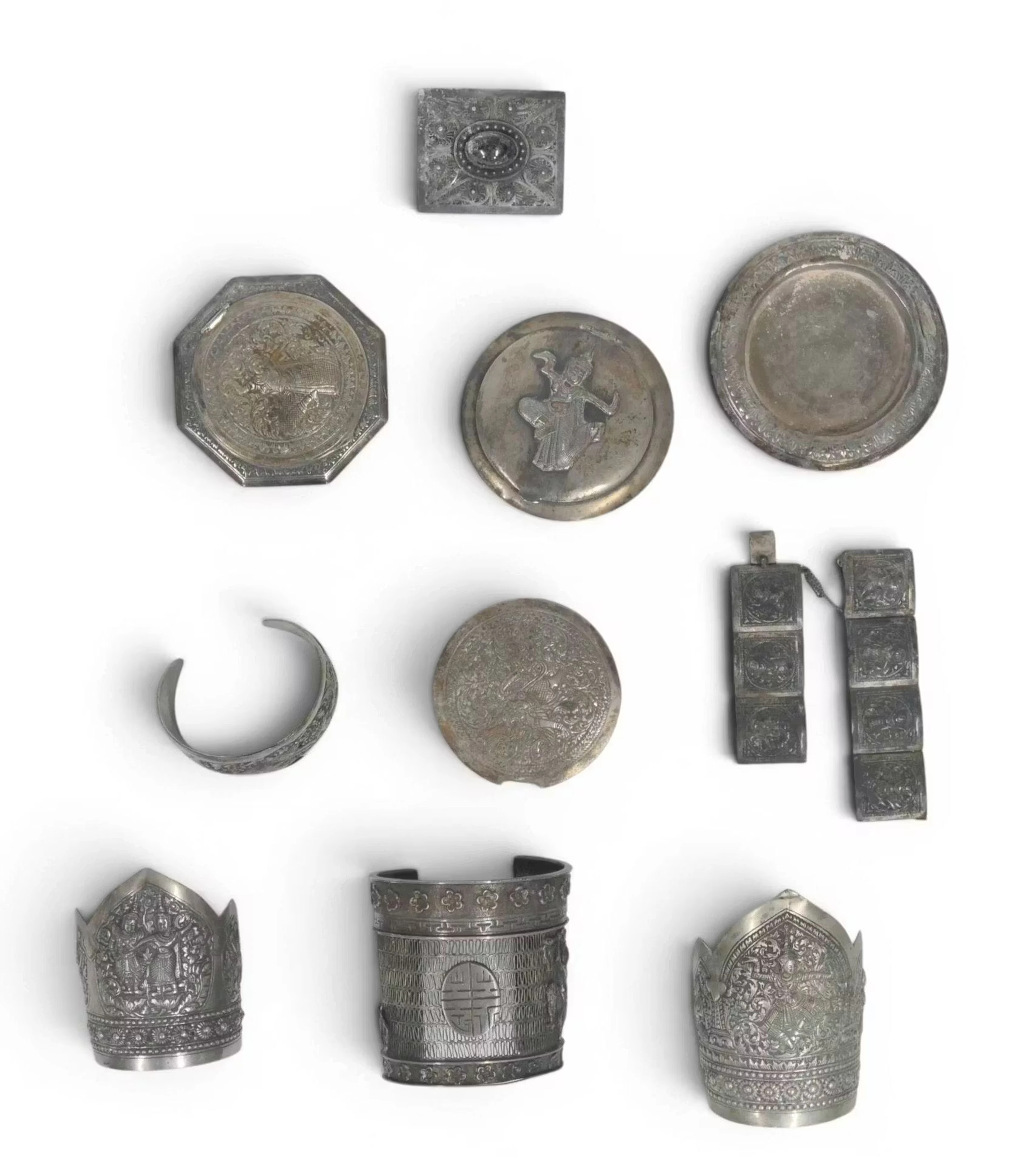 INDOCHINE Lot de neuf pièces en argent (800) comprenant -trois poudriers au décor d'une danseuse -une broche rectangulaire ajourée ornée d'un cabochon -cinq bracelets; trois manchettes aux danseuses, un composé de sept plaquettes carrées, le dernier décoré d'un animal fantastique dans des rinceaux Poids brut total : 500.6 grammes Les poudriers avec deux miroirs : 222.4 grammes Accidents et manques