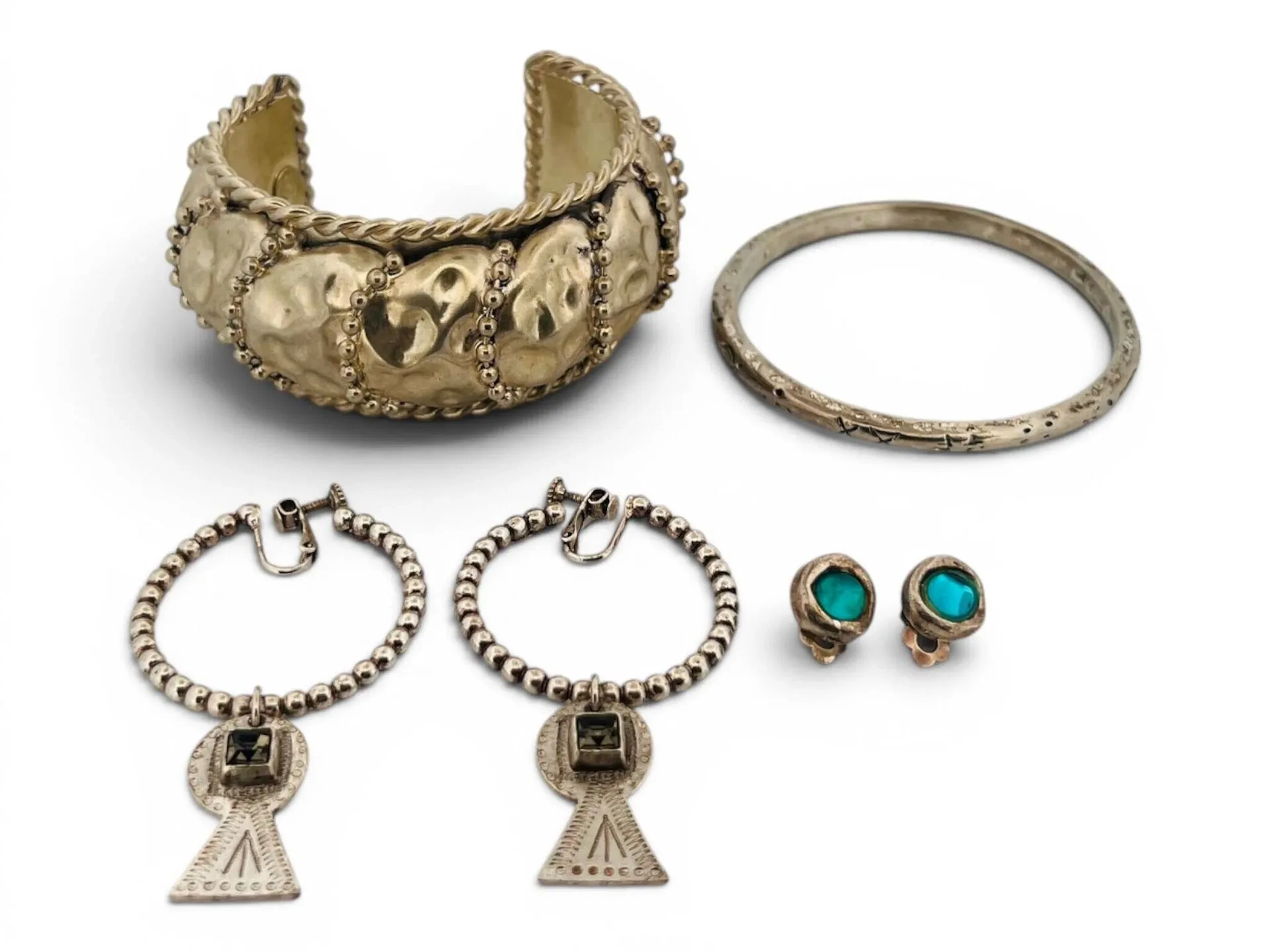 Lot de bijoux fantaisie comprenant: - Jean-Paul GAULTIER Paire de créoles en métal argenté, l'anneau formé de boules et retenant un pendentif stylisant une serrure ornée d'un strass en serti clos. Signées sur l'anneau et le pendentif H. 7 cm Petits éclats aux strass - POGGI Bracelet manchette en métal argenté façon tôle froissée alterné de motifs de chaîne perlées et bordures torsadées. Dim. 6,5 x 7,5 cm - Jonc en métal argenté Diam. 6,5 cm - BICHE DE BERE Paire de clips d'oreilles en métal argenté et cabochons de verre bleu. Diam. 0,9 cm