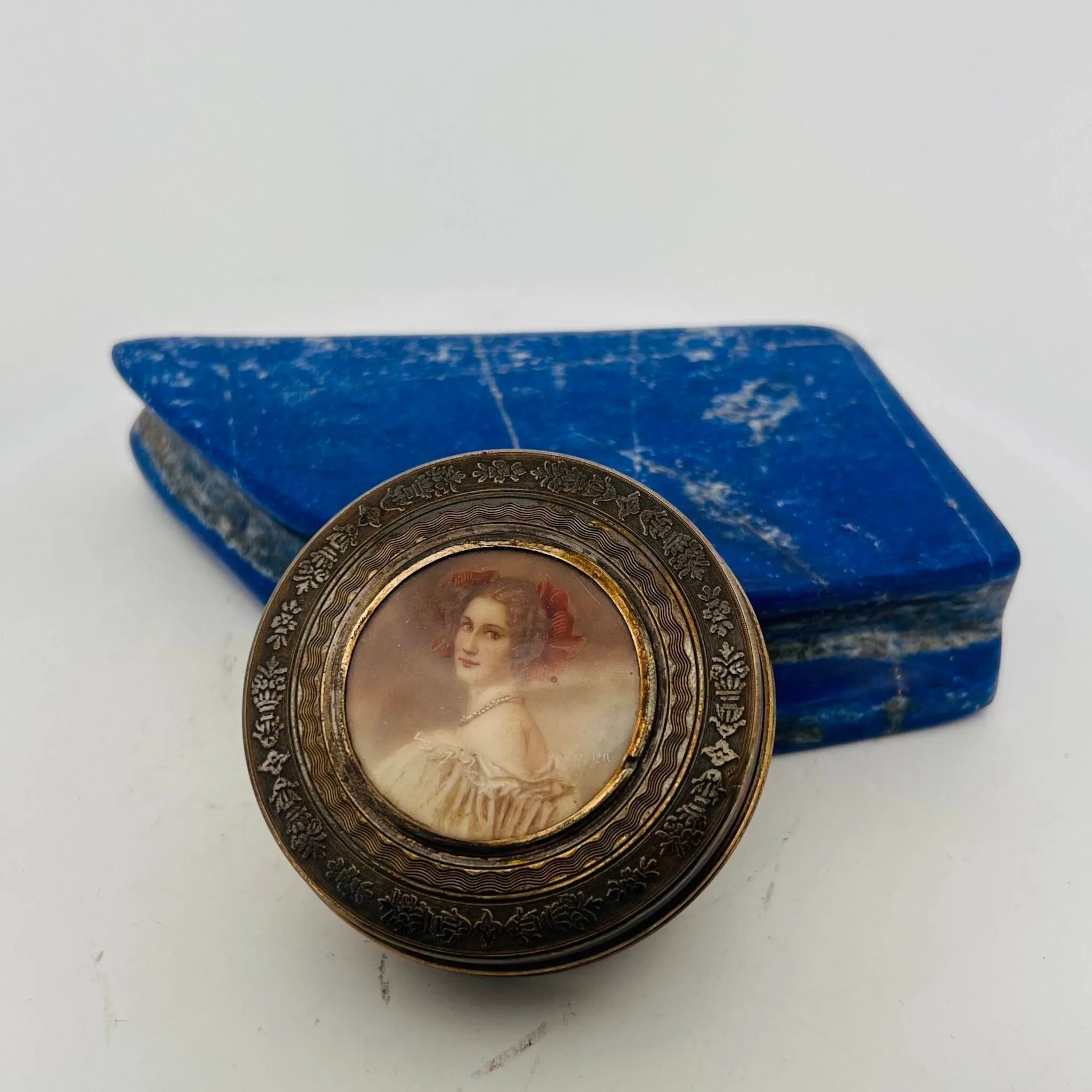 Petite boîte ronde en argent, le couvercle à décor d'une miniature figurant une femme de trois-quarts, le fonds guilloché, l'intérieur en vermeil. Poinçons Minerve. Poids brut 49.40 g - Diam. 64 mm