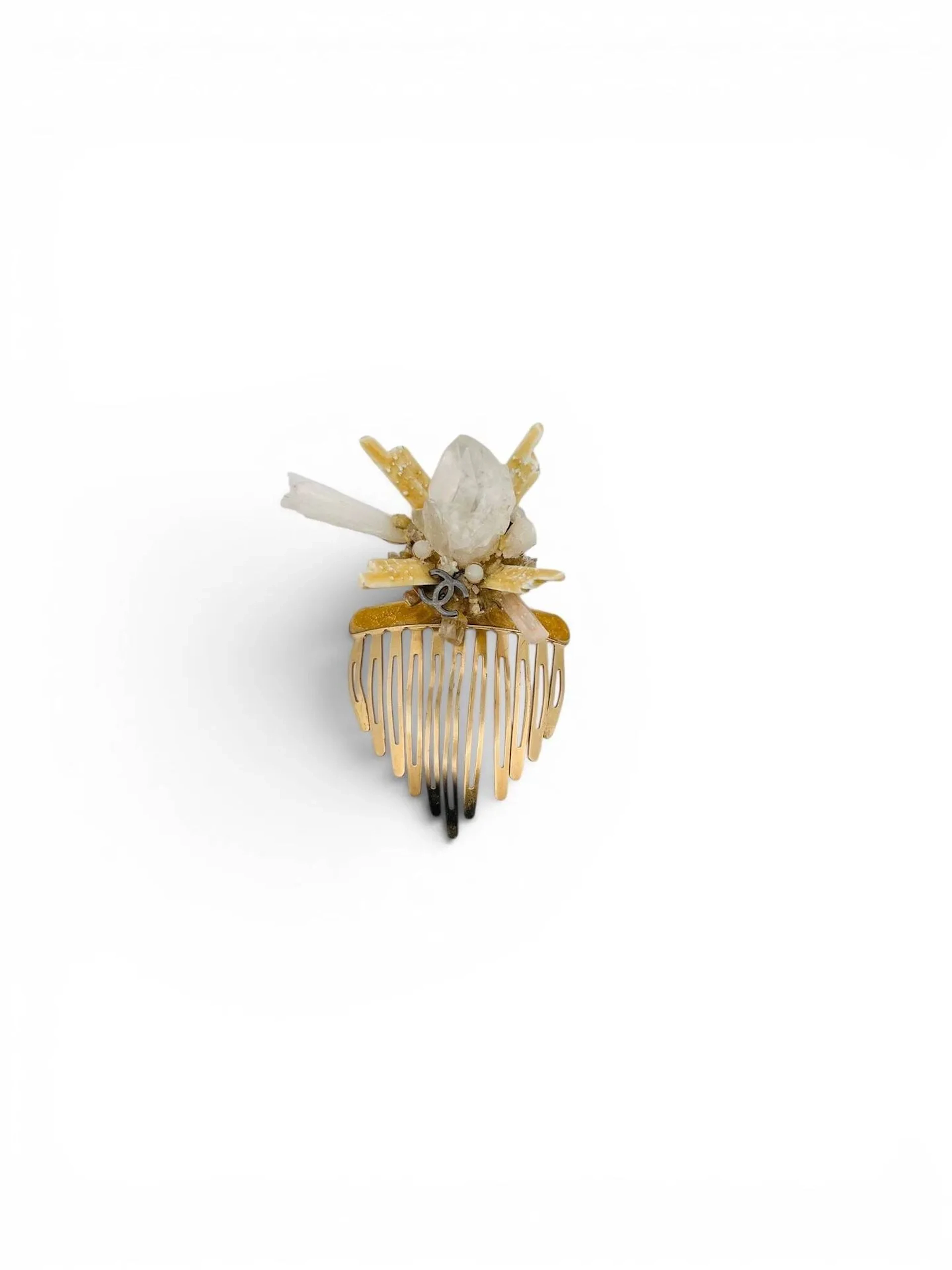Chanel par Karl LAGERFELD (1983 - 2018) Peigne en métal doré/mordoré sommé d'un motif composé de pierres dures (cristal de roche et autres) ainsi que de cabochons de résine, centré du sigle de la marque. Largeur du peigne : 4,8 cm (environ) Rayures, usures et manques Non signé, probablement prototype de défilé