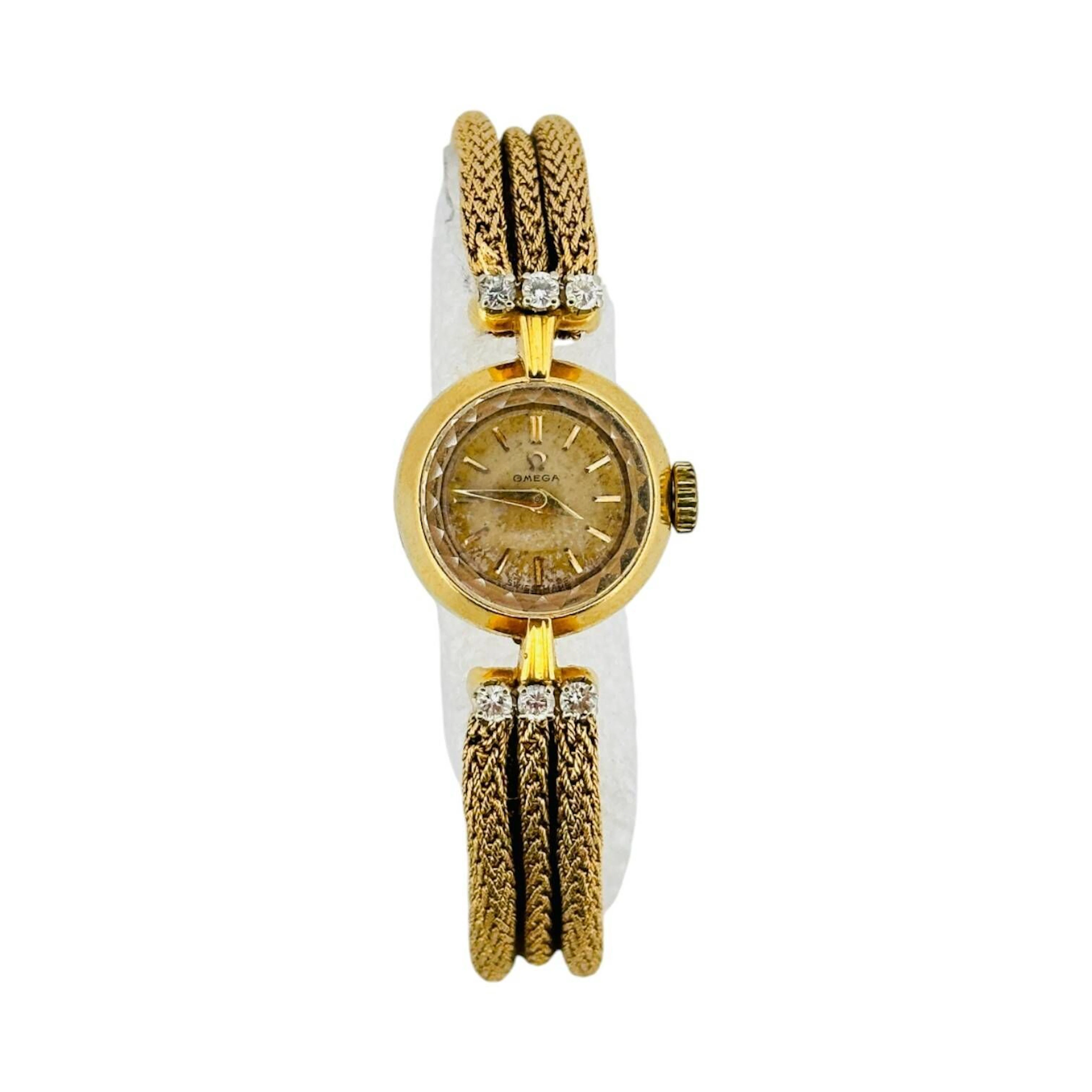OMEGA Montre bracelet de dame en or 18K (750 millièmes), cadran argenté/doré, index en appliques dorées, aiguilles dauphines dorées. Fond clipé en or 18K (750 millièmes), à l’intérieur signé Omega, référence 7049, numéroté 11384845. Mouvement mécanique à remontage manuel signé OMEGA, calibre 480, numéroté 14691987. Anses serties de diamants taille brillant. Bracelet en or 18K (750 millièmes), fermeture à glissière avec sécurité. Montre fonctionnelle lors de l’expertise, sans garantie de fonctionnement futur et d’état des pièces. Légères rayures et marques au boitier, quelques traces au cadran, d’origine argenté qui a pris une patine dorée. Travail suisse vers 1954 Poids brut 31,2 g Diamètre17mm, pour un poignet d’environ 15 cm
