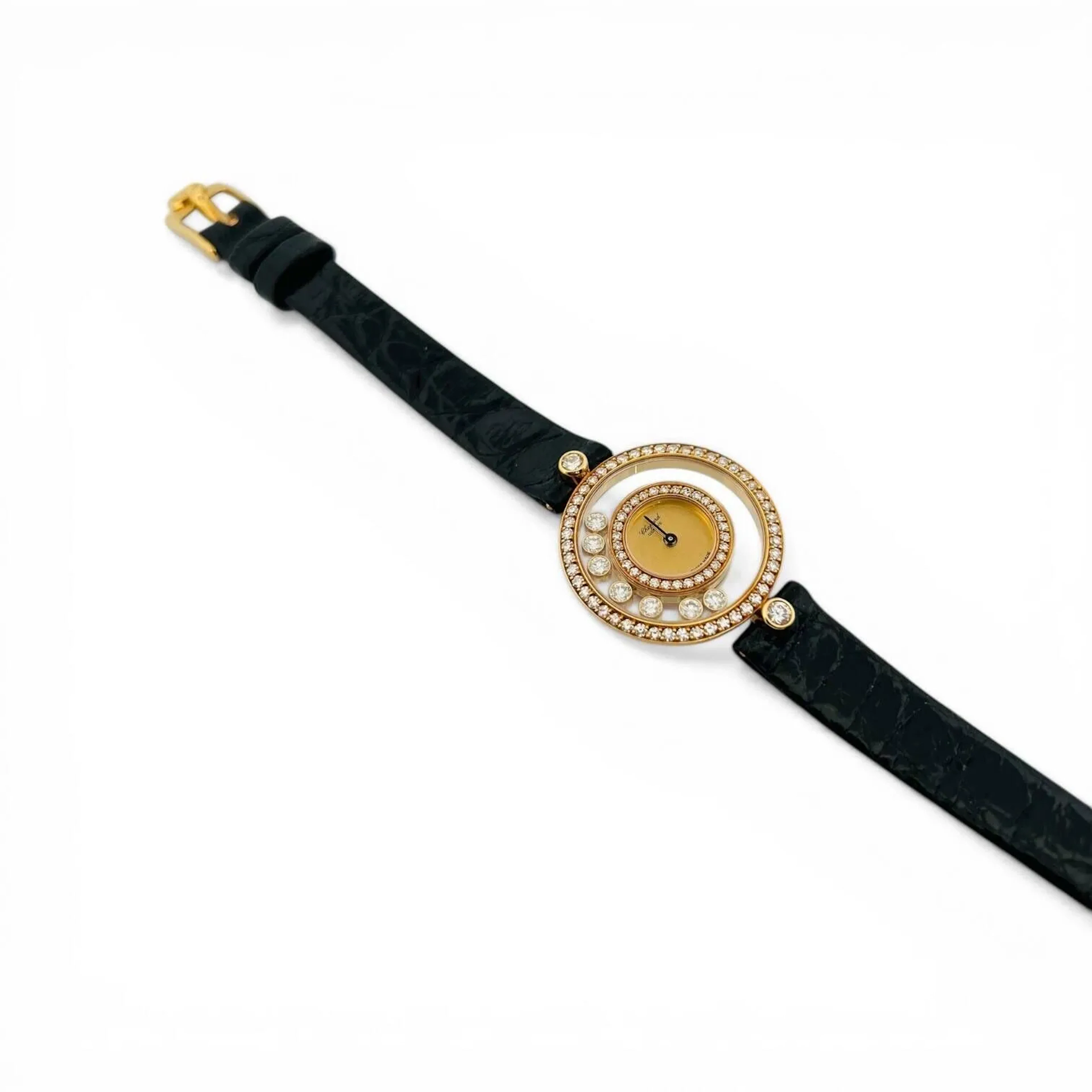 CHOPARD HAPPY DIAMONDS Montre-bracelet en or 18K (750 millièmes), autour du cadran un cerclage en or 18K (750 millièmes) serti de diamants taille brillant, et verre saphir, encerclant sept diamants taille brillant en circulation libre, au centre cadran doré, aiguilles dorées. Fond clipé en or 18K (750 millièmes) signé Chopard, référence 4097, numéroté, correcteur permettant la mise à l’heure par stylet. Mouvement à quartz. Anses serties chacune d’un diamant taille brillant. Bracelet en cuir noir signé Chopard, boucle ardillon en or 18K (750 millièmes) signée Chopard. Montre non fonctionnelle lors de l’expertise, sans garantie de fonctionnement futur et d’état des pièces. Rayures d’usage au boitier. Accompagnée de sa boite, son stylet, et les instructions de mise à l’heure. Vers 1990 Poids brut 18,1 g Diamètre 24 mm