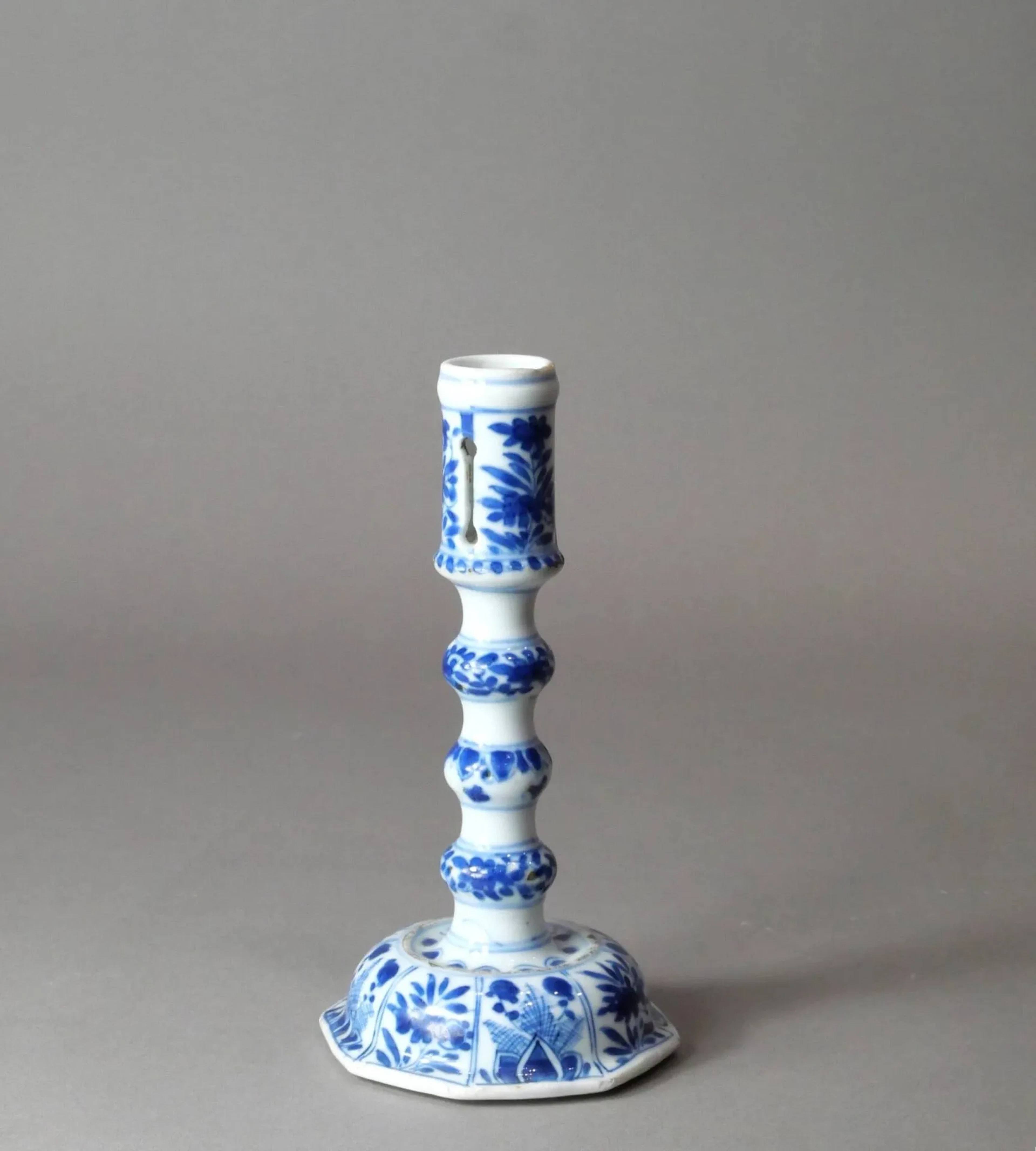 CHINE - Époque KANGXI (1662-1722) Bougeoir en porcelaine à décor en bleu et blanc de végétaux et motifs stylisés. Production destinée au marché européen, inspiré des bougeoirs en laiton ou en argent. H : 18.5 cm Un modèle similaire a été vendu le 7 mai 2020 (Christie’s New York, lot 195)