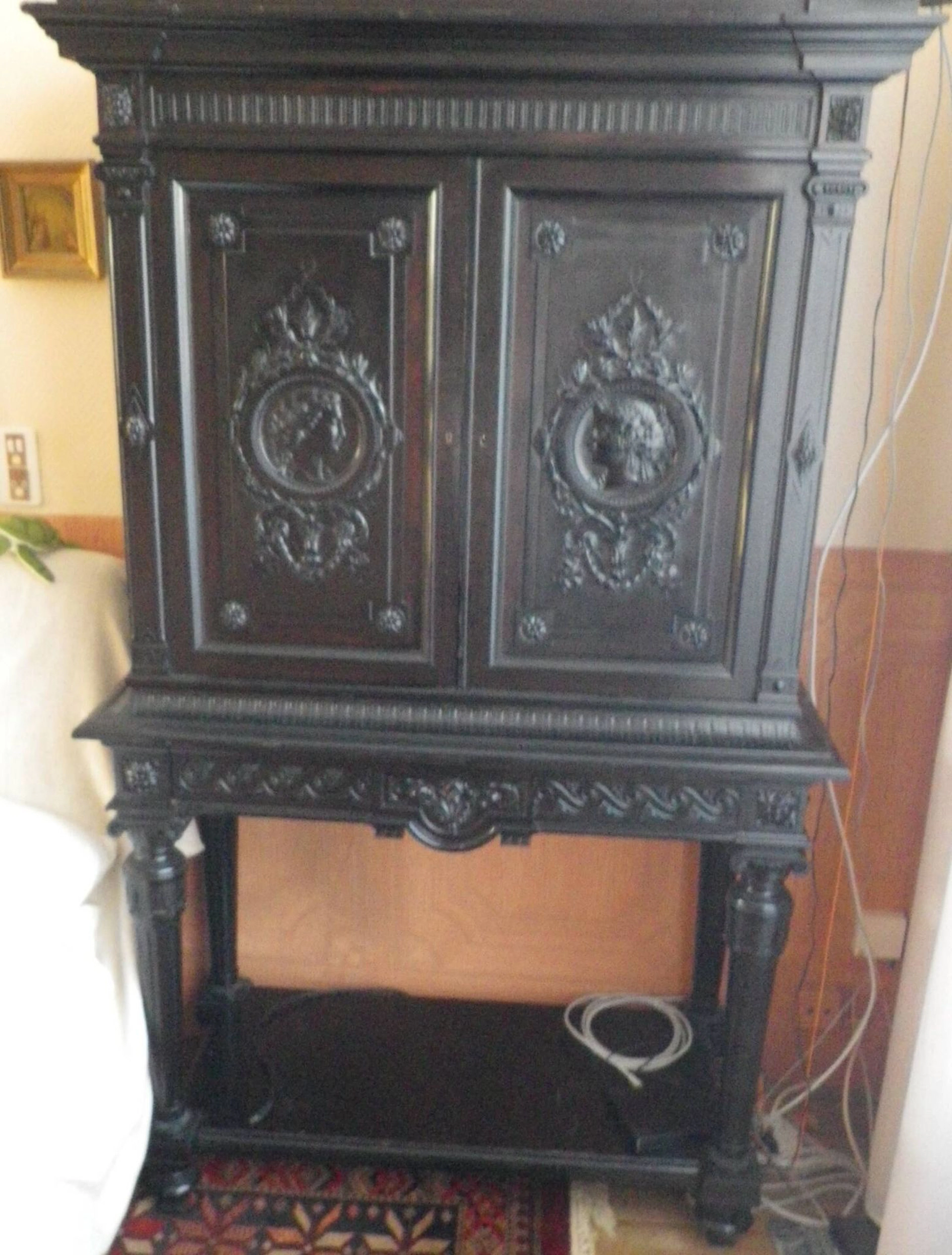 A blackened wooden cabinet with a double-door front featurin - Lot 386