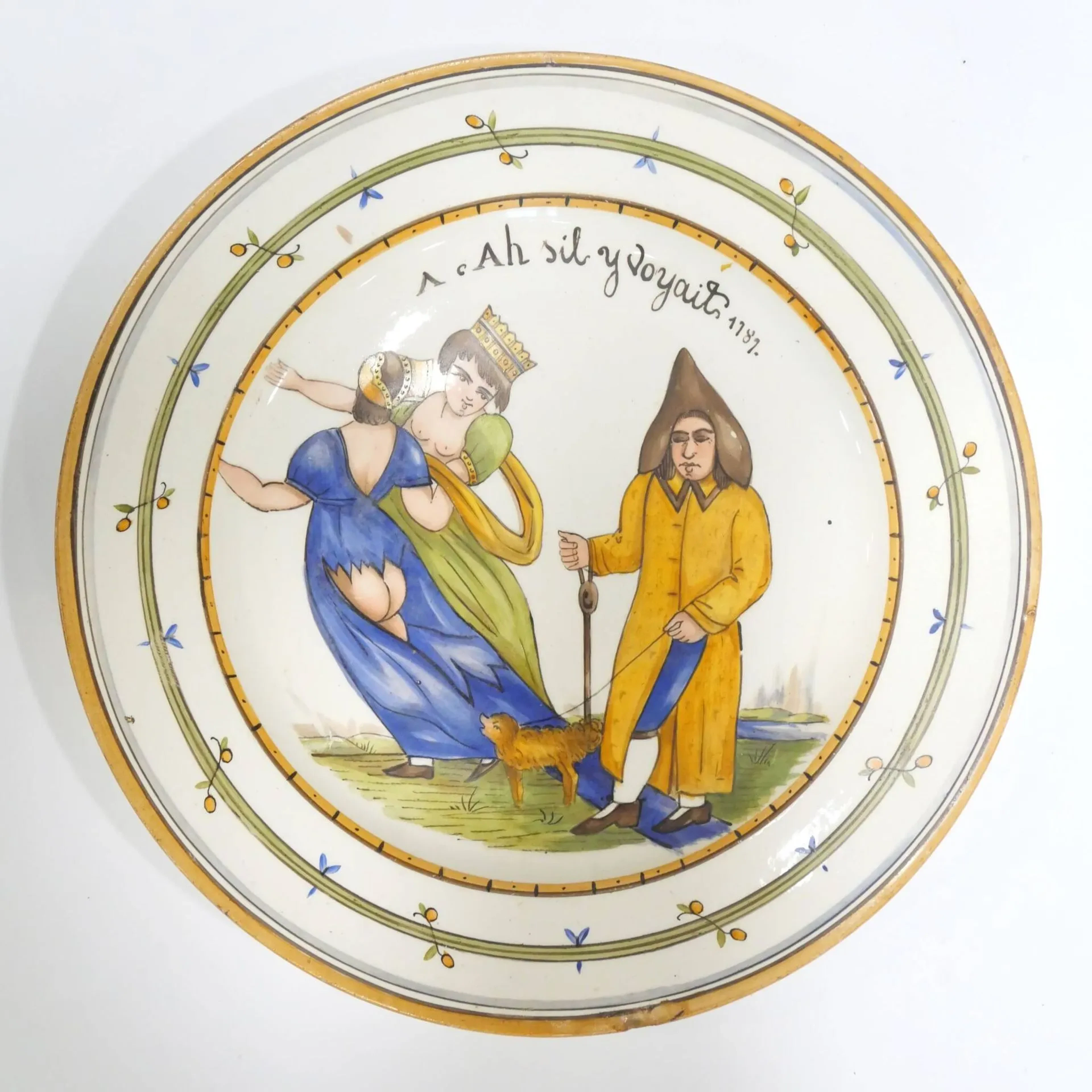 CURIOSA Assiette en faïence, à décor polychrome d'un aveugle et de deux femmes, l'une les fesses à l'air, l'autre la poitrine dénudée, sommé de la légende " Ah s'il y voyait 1787 ". XXème siècle. Diam. 24.50 cm - Un éclat à 6 h. Note : le musée de Reims a dans ses collections une assiette de Nevers du XVIIIème siècle avec ce même décor.