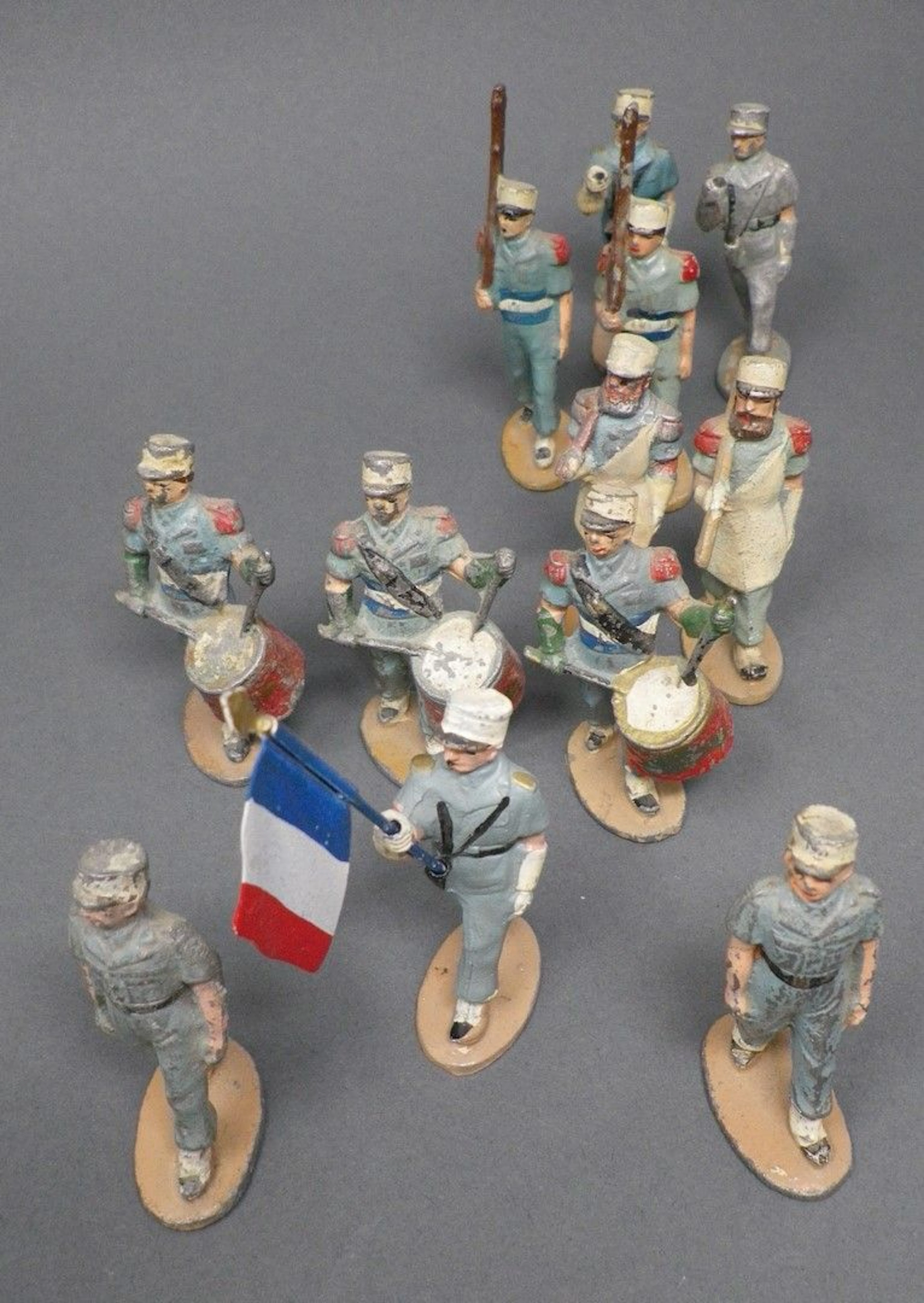 QUIRALU - Infanterie Légion au défilé (1955-1960) Douze figurines dont en uniformes bleu vert :deux pionniers avec hache, le porte-drapeau, trois tambours, reproduits p. 102 & 103 - Bibliographie : Les jouets Quiralu 1933-1964 - R. Alazet - J. Borsarello - H. Giroud - Ed° J. Granchet Paris. Jouets anciens pouvant présenter des manques de peinture, des chocs ou des manques, y compris pour les conditionnements éventuels. Vendus en l'état et sans réclamations.