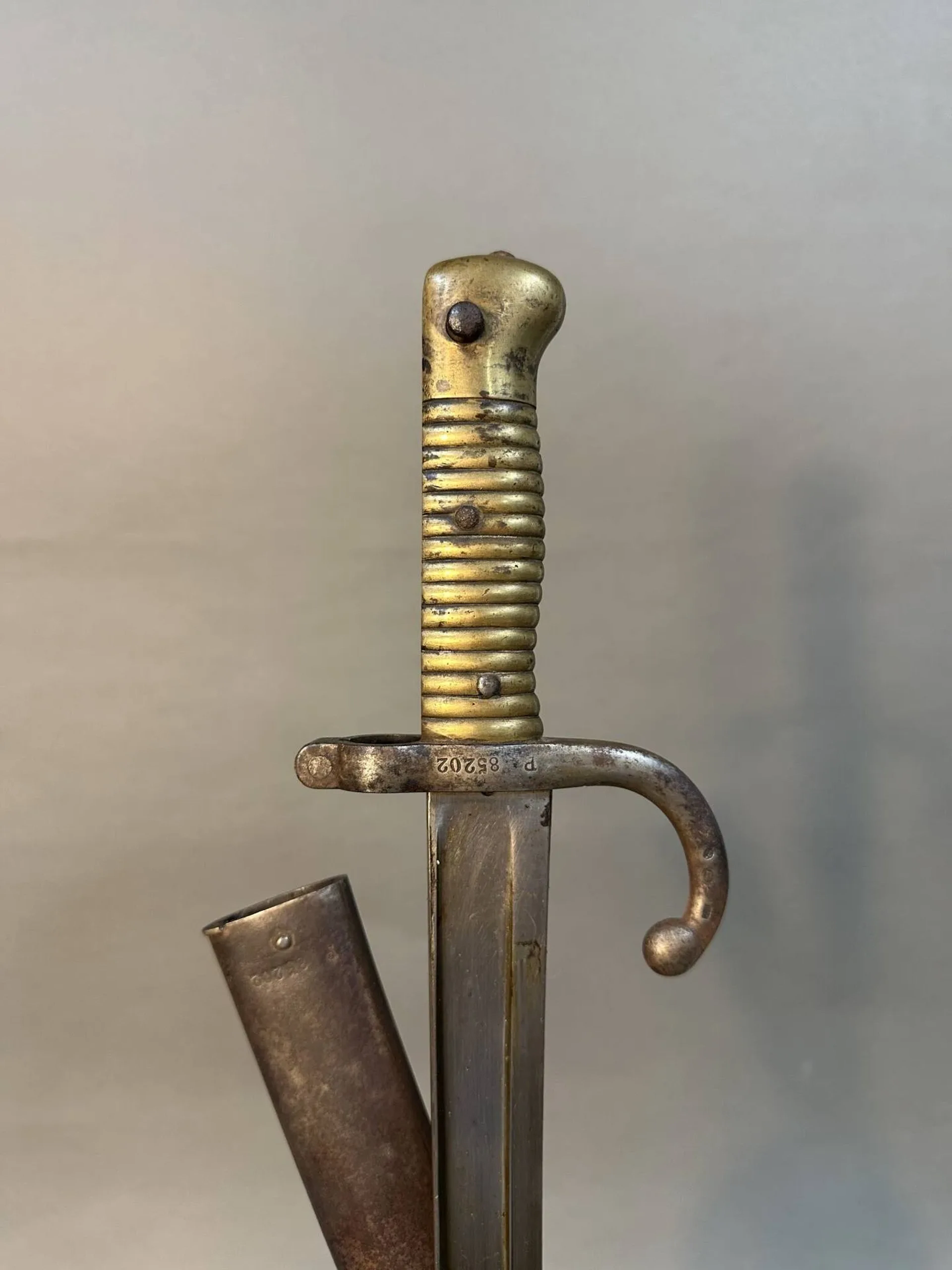 Baïonnette modèle 1866 pour fusil Chassepot. Monture en laiton et quillon fer. Lame à la yatagan de la manufacture de Saint Etienne, date 1873. Fourreau en acier au même numéro. Longueur totale: 69 cm. France, Époque troisième république.