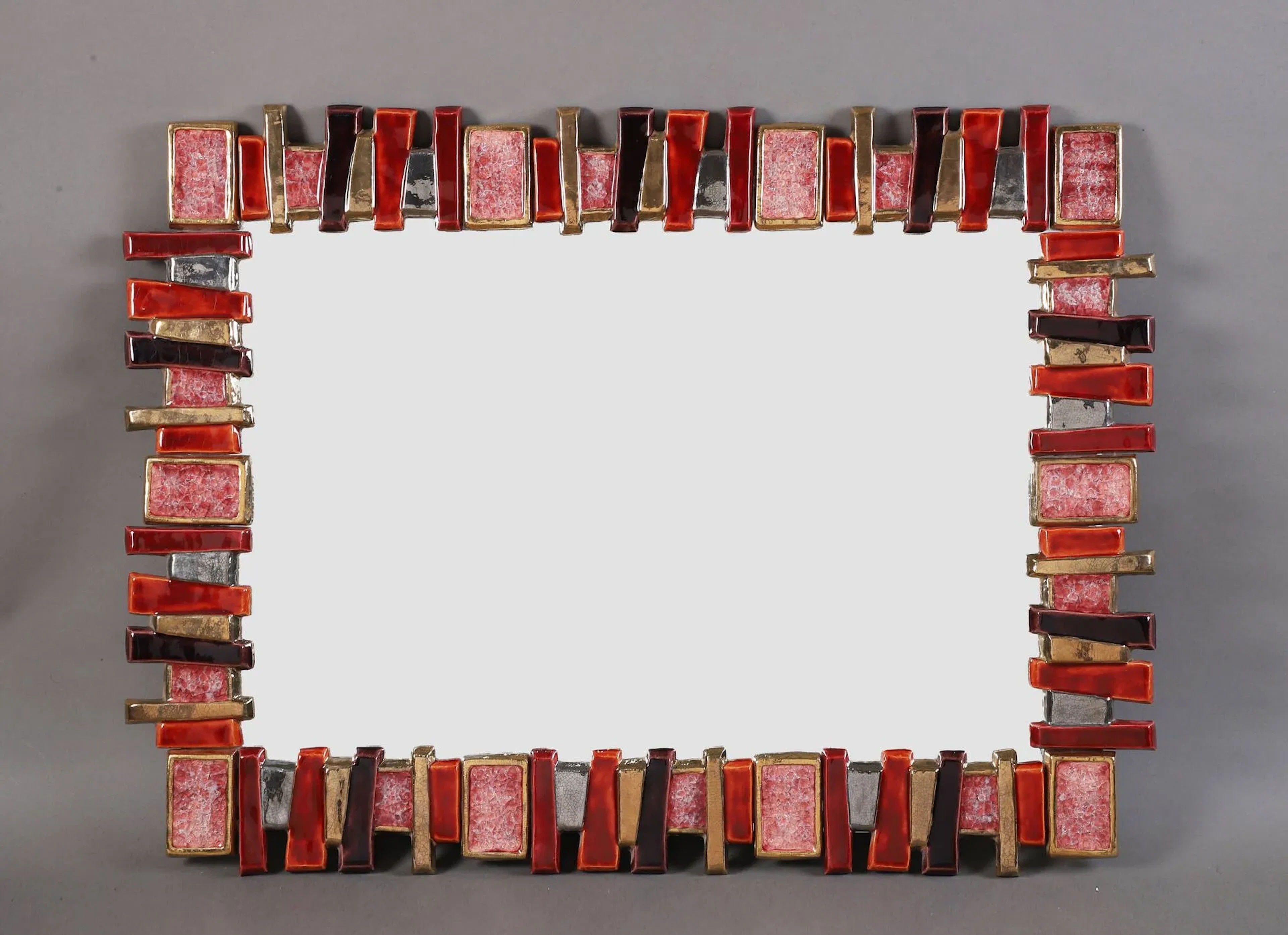 Marion de CRECY (1954) Miroir mural rectangulaire Épreuve en céramique émaillée or, rouge, violet et verre cristallisé, monté sur un panneau de bois Non signé H. : 81 cm. – L. : 61 cm.