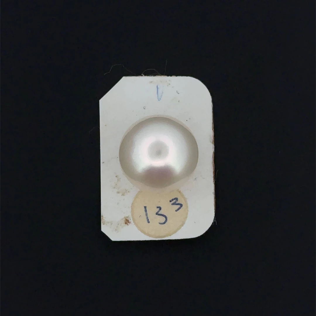 A slightly pinkish white cultured pearl in a button shape. - Lot 209