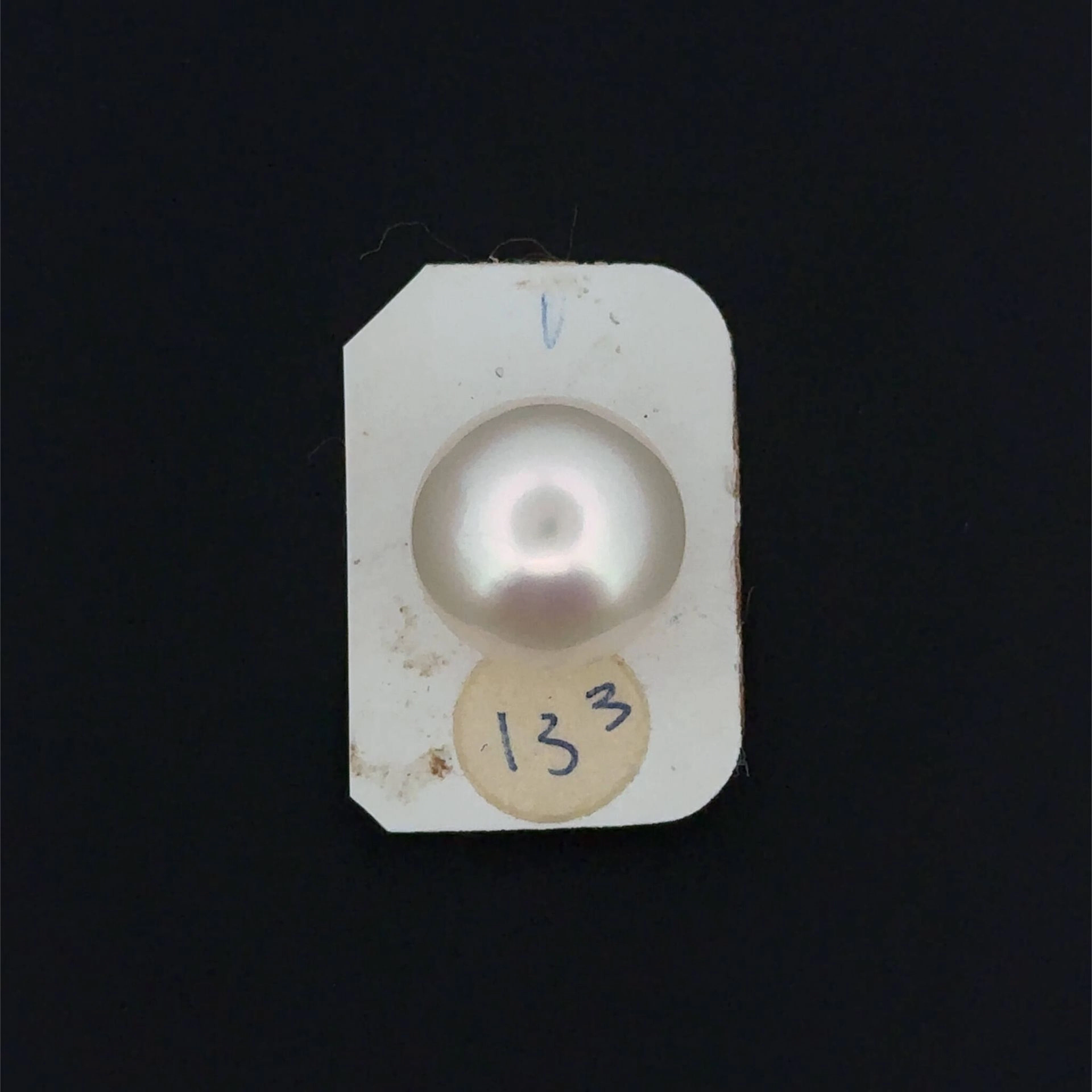 A slightly pinkish white cultured pearl in a button shape. - Lot 209