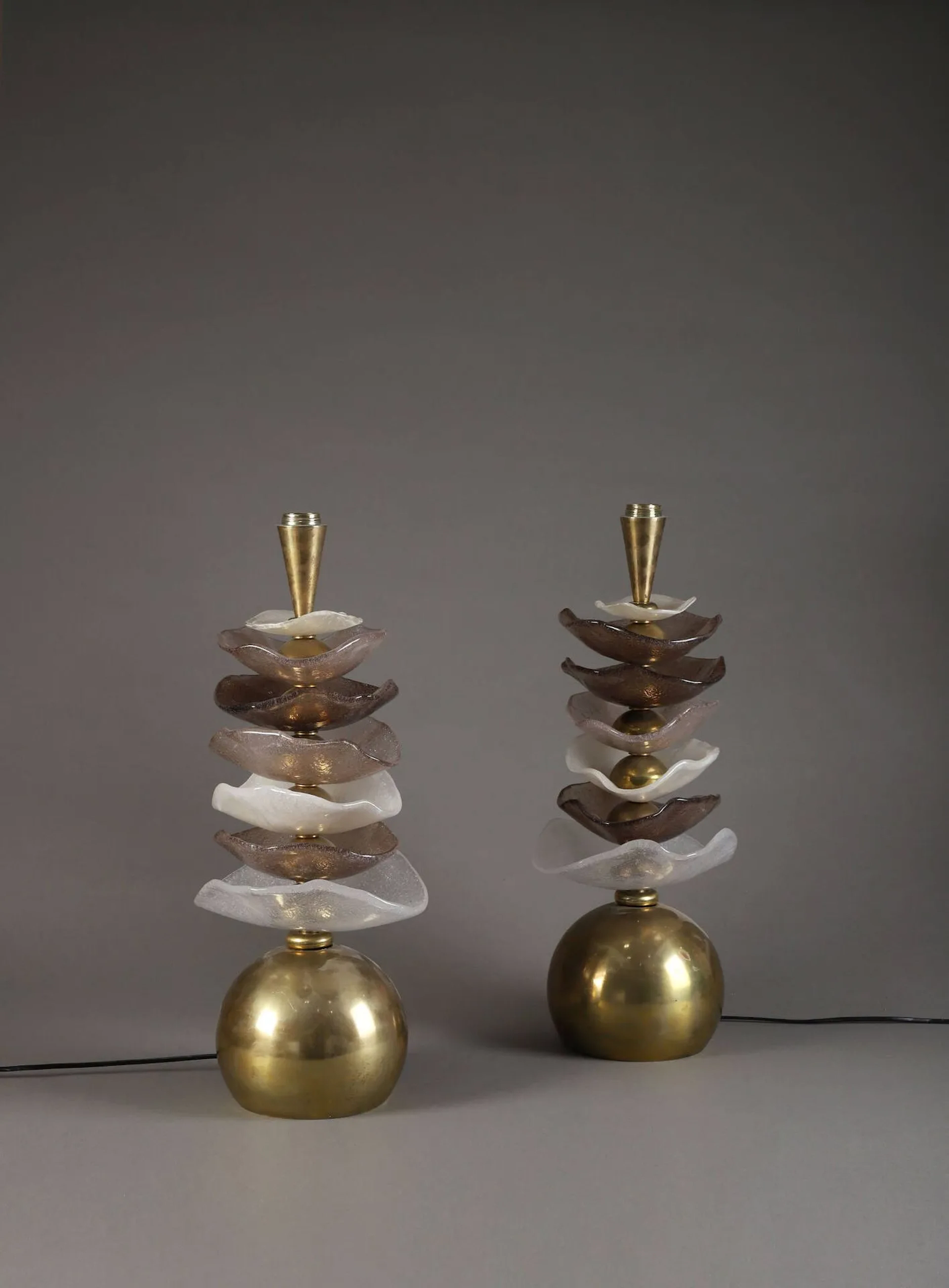 TRAVAIL ITALIEN (XX) Paire de pieds de lampes, circa 2010, à base circulaire d'où s'élève un fût rythmé d'une superposition de coupelles en verre blanc et brun et de bagues semi sphériques en laiton. (Rayures, oxydations) H. : 50 cm. (sans la douille)