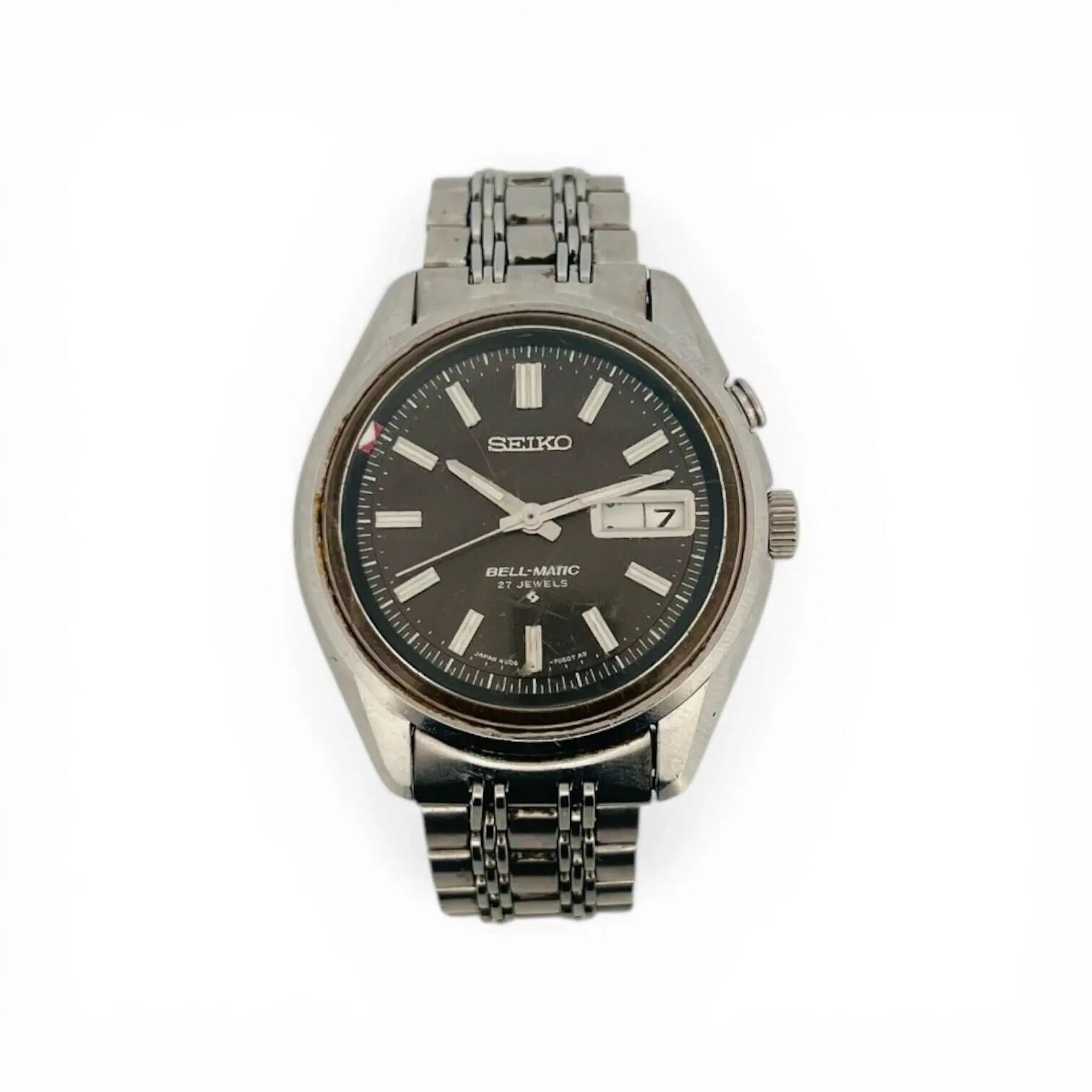 SEIKO BELLMATIC Montre-bracelet à alarme en acier, cadran gris soleillé, minuterie traits blancs, index des heures en appliques argentées avec insert blanc au centre, aiguilles glaives facettées argentées, jour et date à trois heures, rehaut tournant pour régler l’alarme. Fond de boitier vissé signé Seiko, référence 4006-7011, numéroté 052010. Mouvement mécanique à remontage automatique signé Seiko, calibre 4006A. Bracelet en acier, fermeture boucle déployante signée Seiko, pièces de bout mention XAB/021. Mouvement et alarme fonctionnels lors de l’expertise, sans garantie dans le temps, état des pièces non garanti. Rayures au boitier et au bracelet, rayures importantes au verre. Vers 1980 Diamètre 38 mm Expertise : Nicolas Amsellem