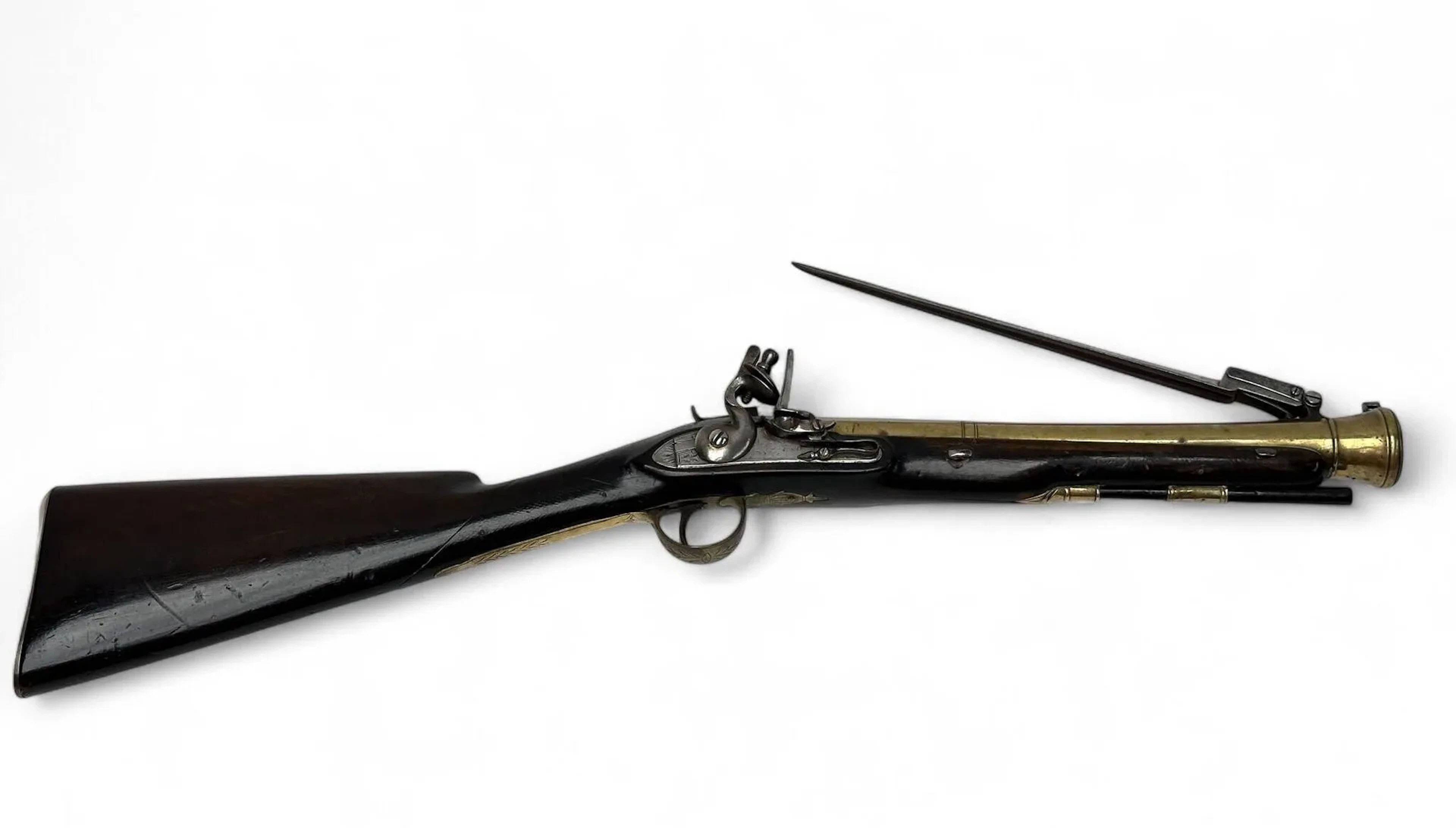 Fusil tromblon de marine britannique à baïonnette lancée. Platine à silex à corps plat et chien en col de cygne. (sécurité enlevée). Canon tromblon à double registre et boulet de renfort à la bouche. Poinçons de Birmingham au tonnerre et reste de signature sur le pan supérieur du canon. Crosse en noyer, toute garniture laiton. Baïonnette lancée avec système de déverrouillage derrière la queue de culasse. Bonne mécanique. Longueur totale: 76 cm. Travaille anglais vers 1780. Arme de catégorie D.