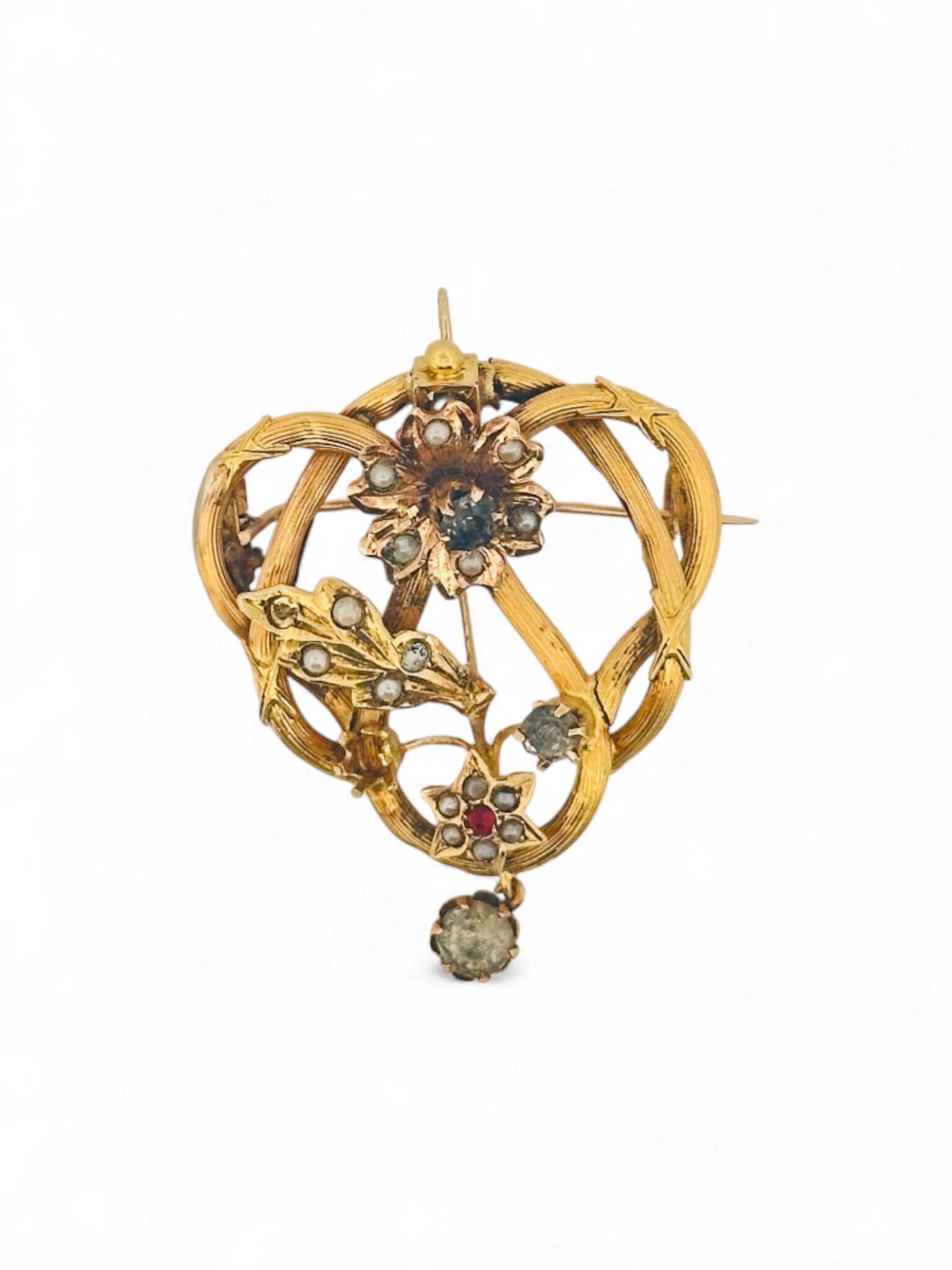 Broche-pendentif en or jaune 18K (750) ajouré à décor floral sertie de petites perles et pâtes de verre se terminant par une pampille sertie d'une pierre blanche. Poids brut : 4.53 g. (accidents, réparations et manques)