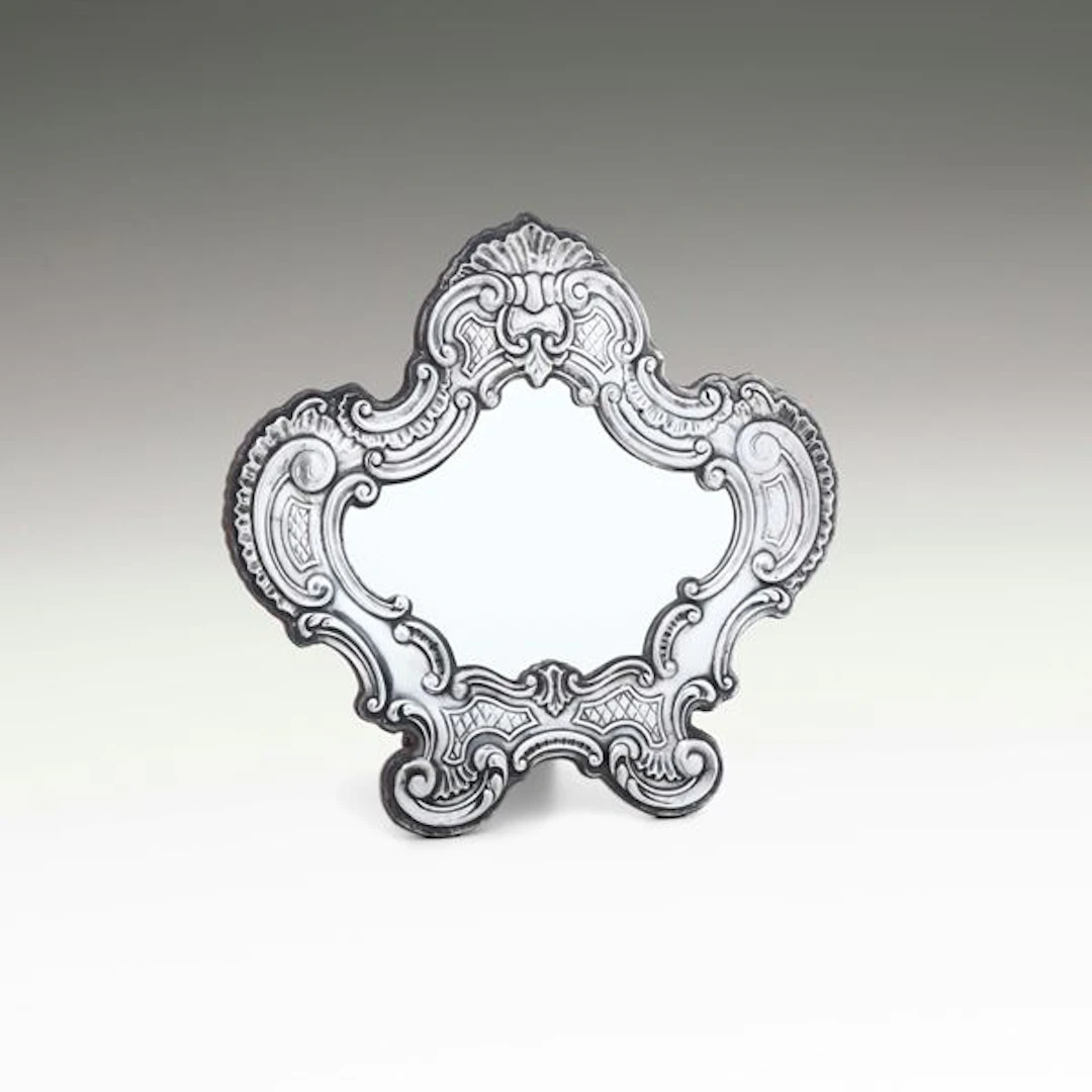 Uno specchio da tavolo con cornice di gusto barocco. Argenteria artistica