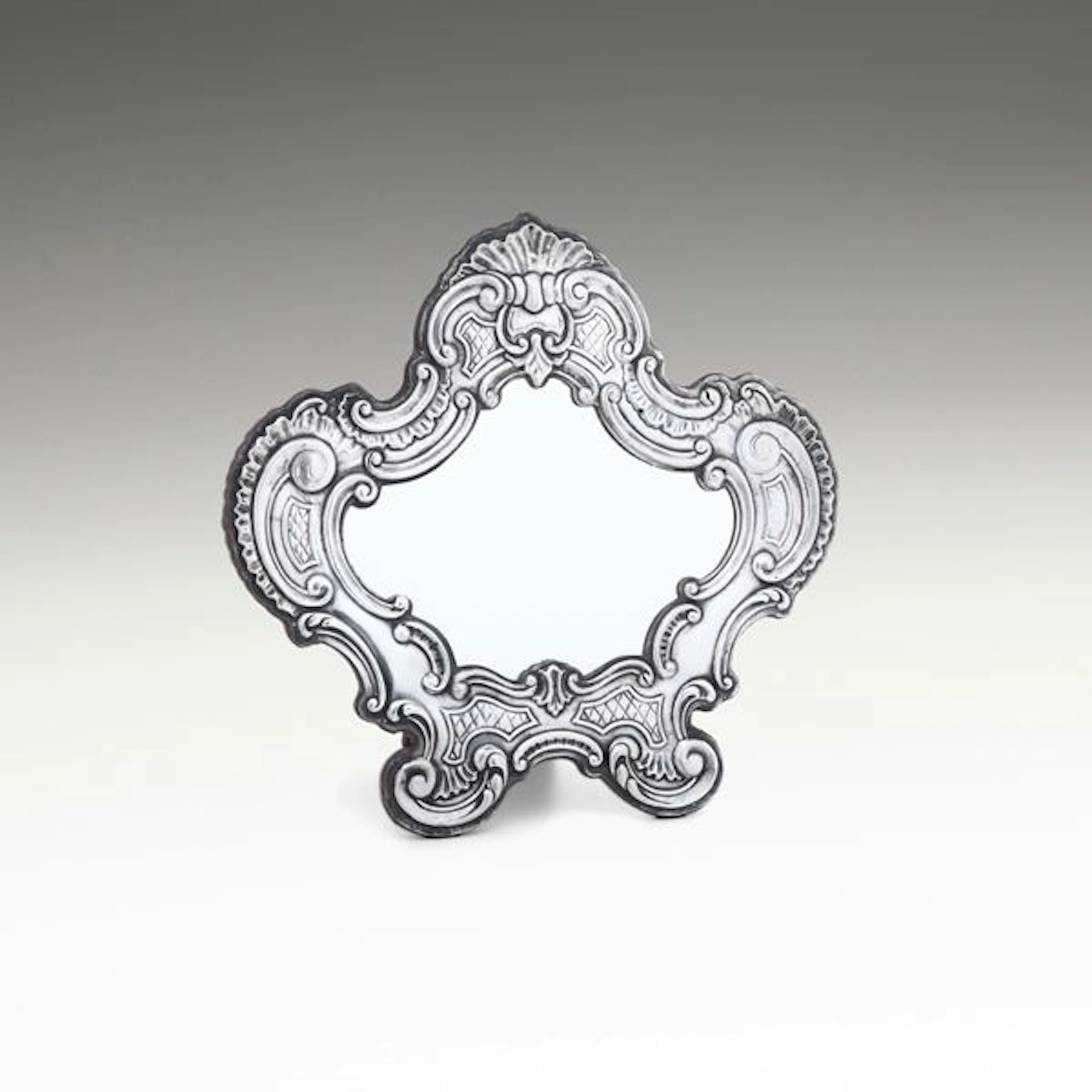 Uno specchio da tavolo con cornice di gusto barocco. Argenteria artistica