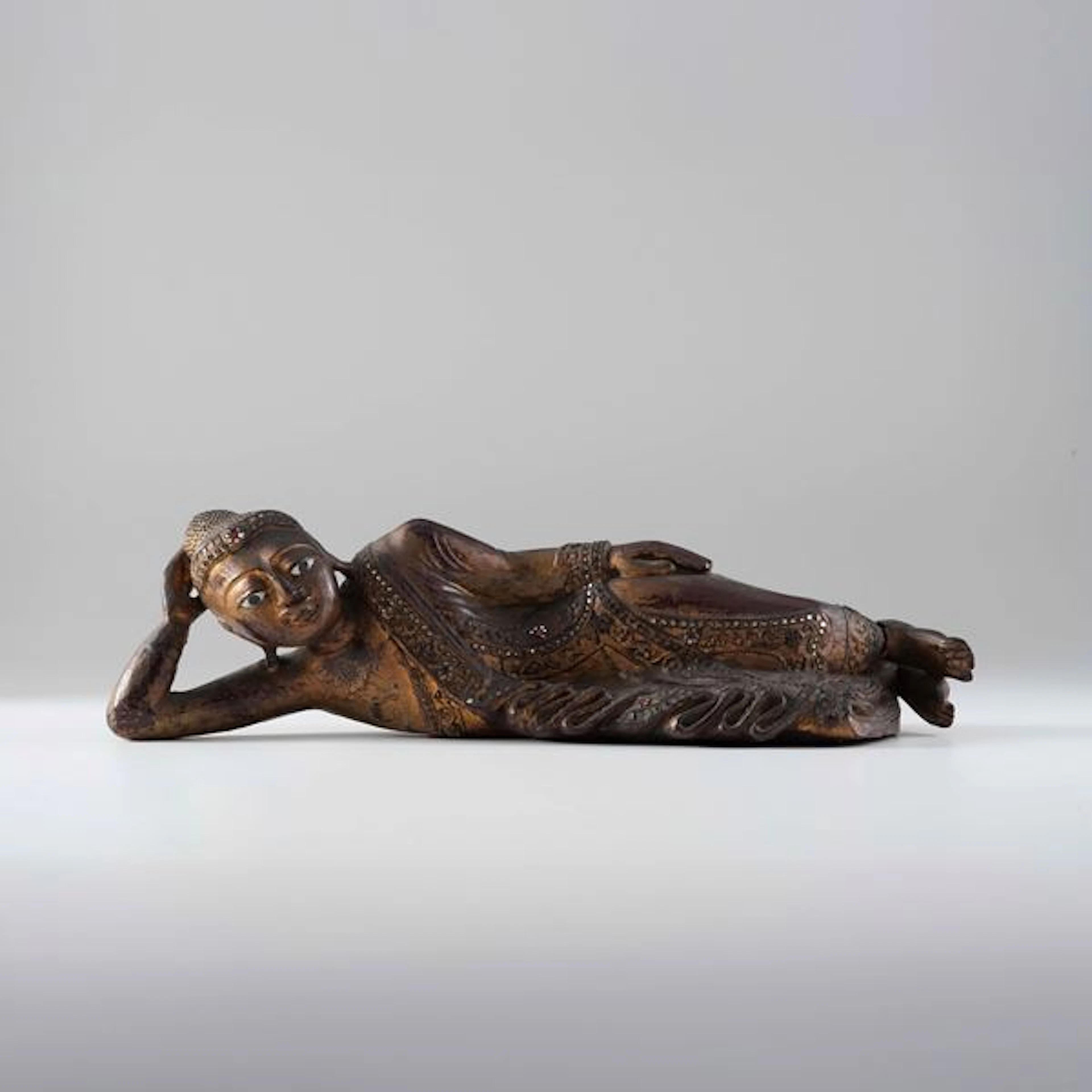 Figura di Buddha Parinirvana in legno dorato con inserti di pietre