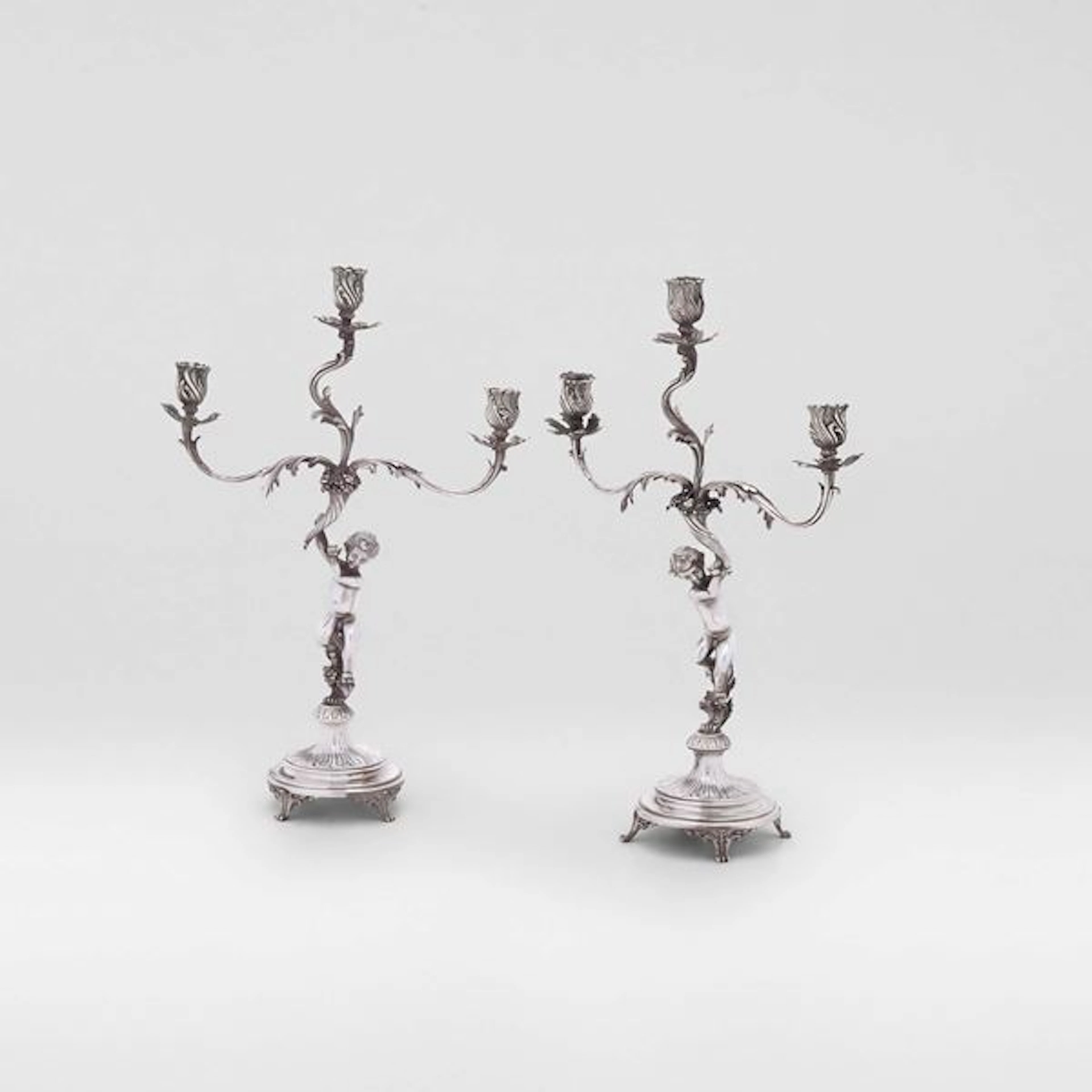 Coppia di candelabri a tre fiamme di gusto neobarocco. Argenteria