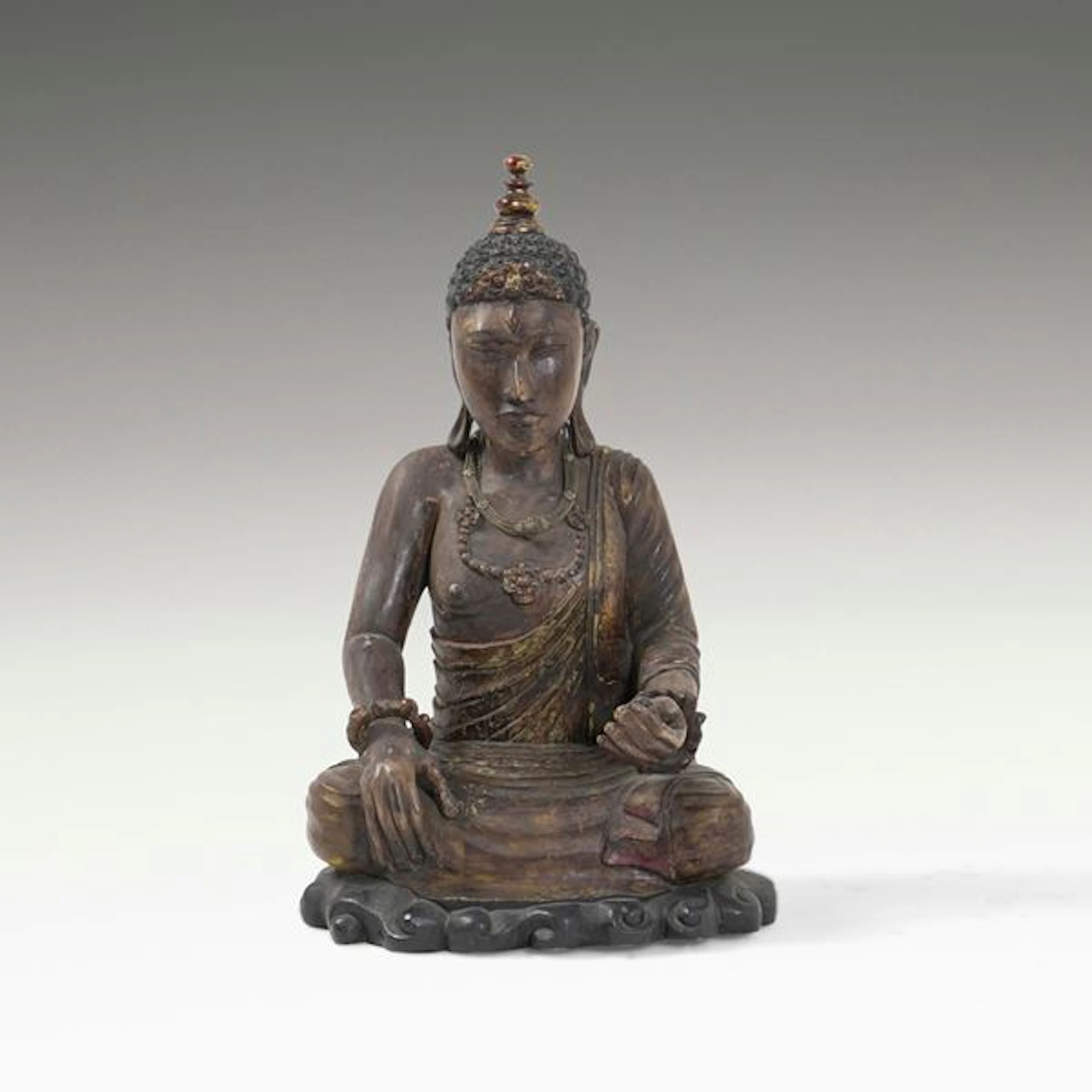 Figura di Buddha in legno con tracce di policromia e collane in materiali