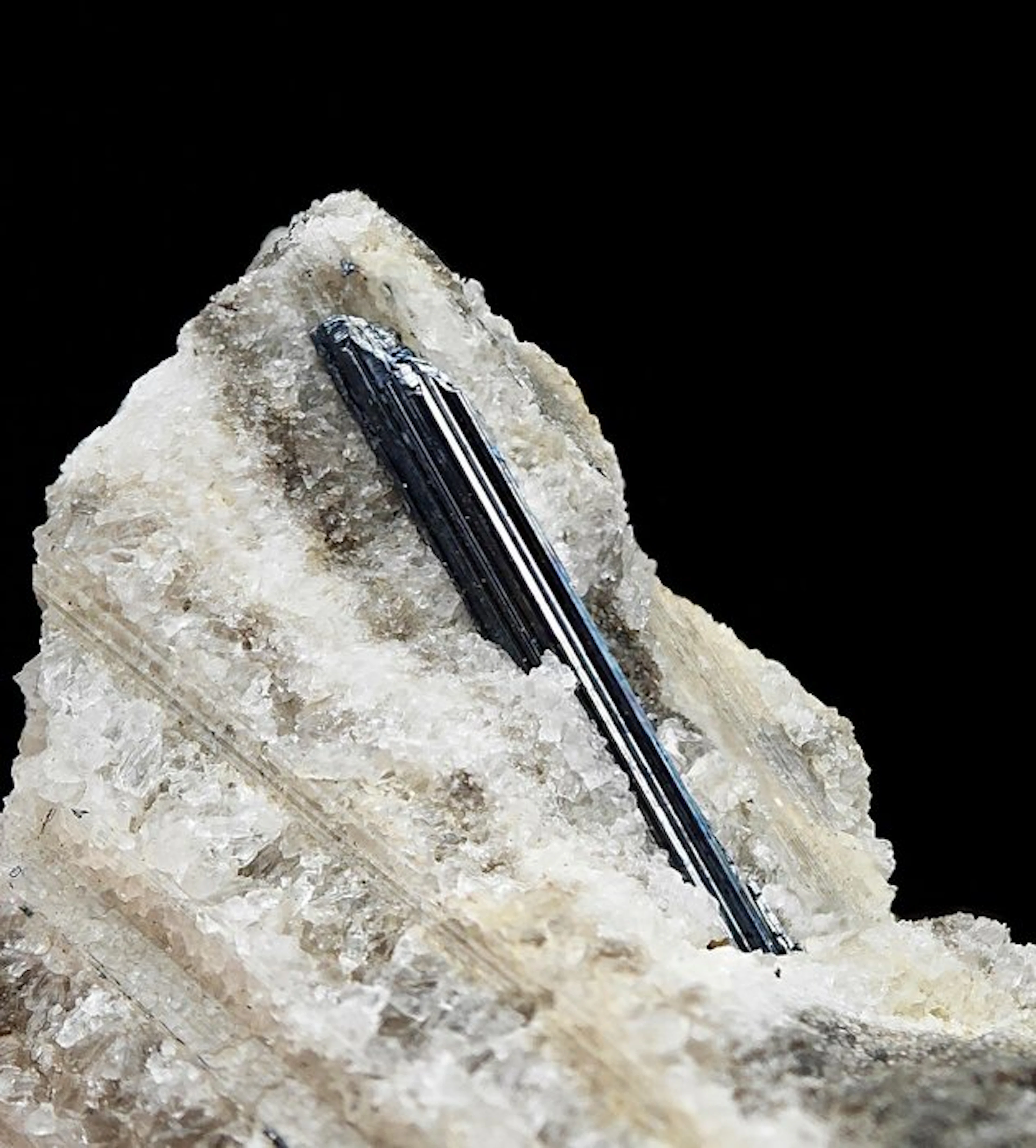 Rare, lustrous stibnite set in red fluorescent calcite