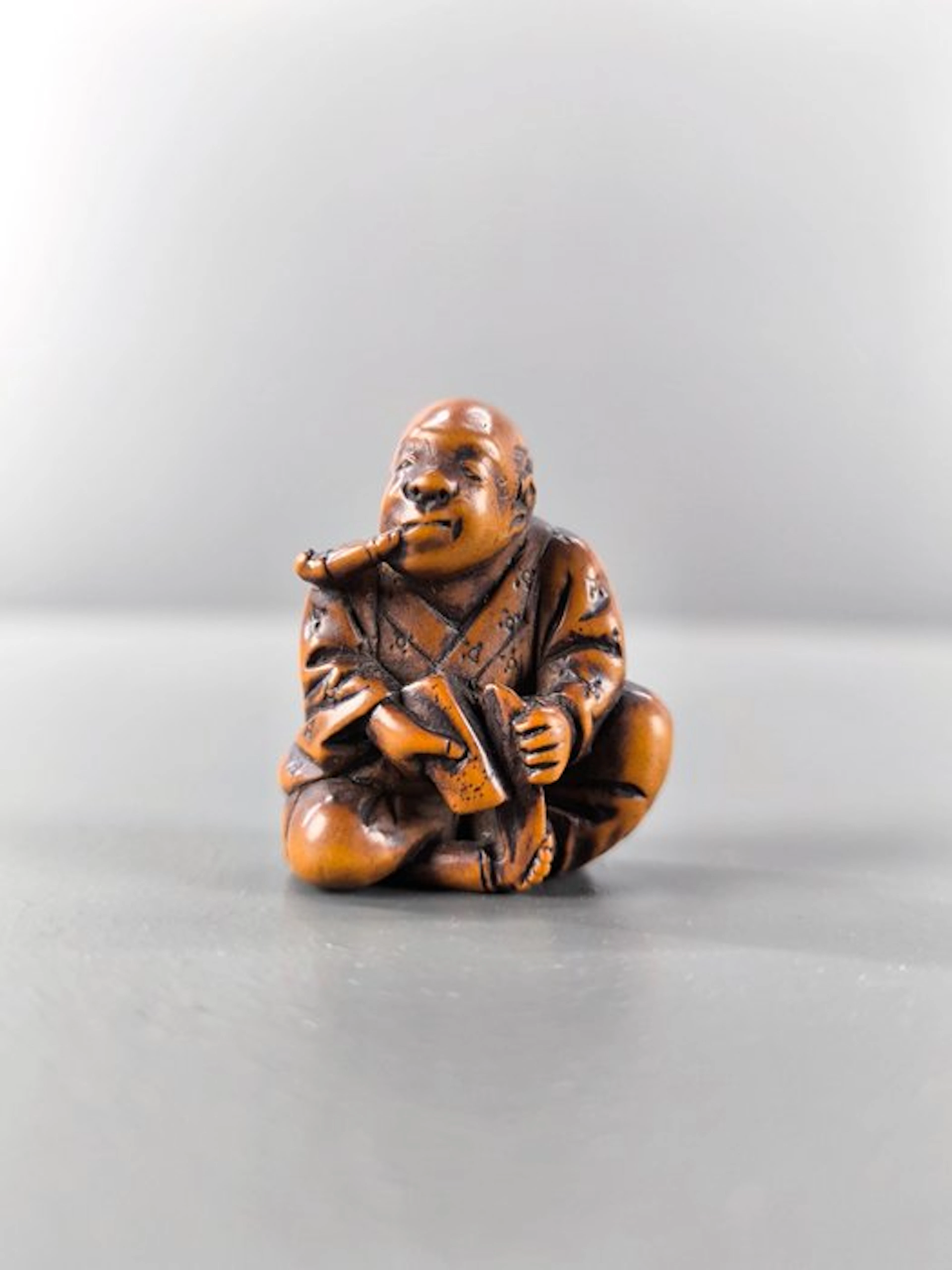 Japan Wood A katabori netsuke depicting a man smoking a pipe. - 3.8 cm