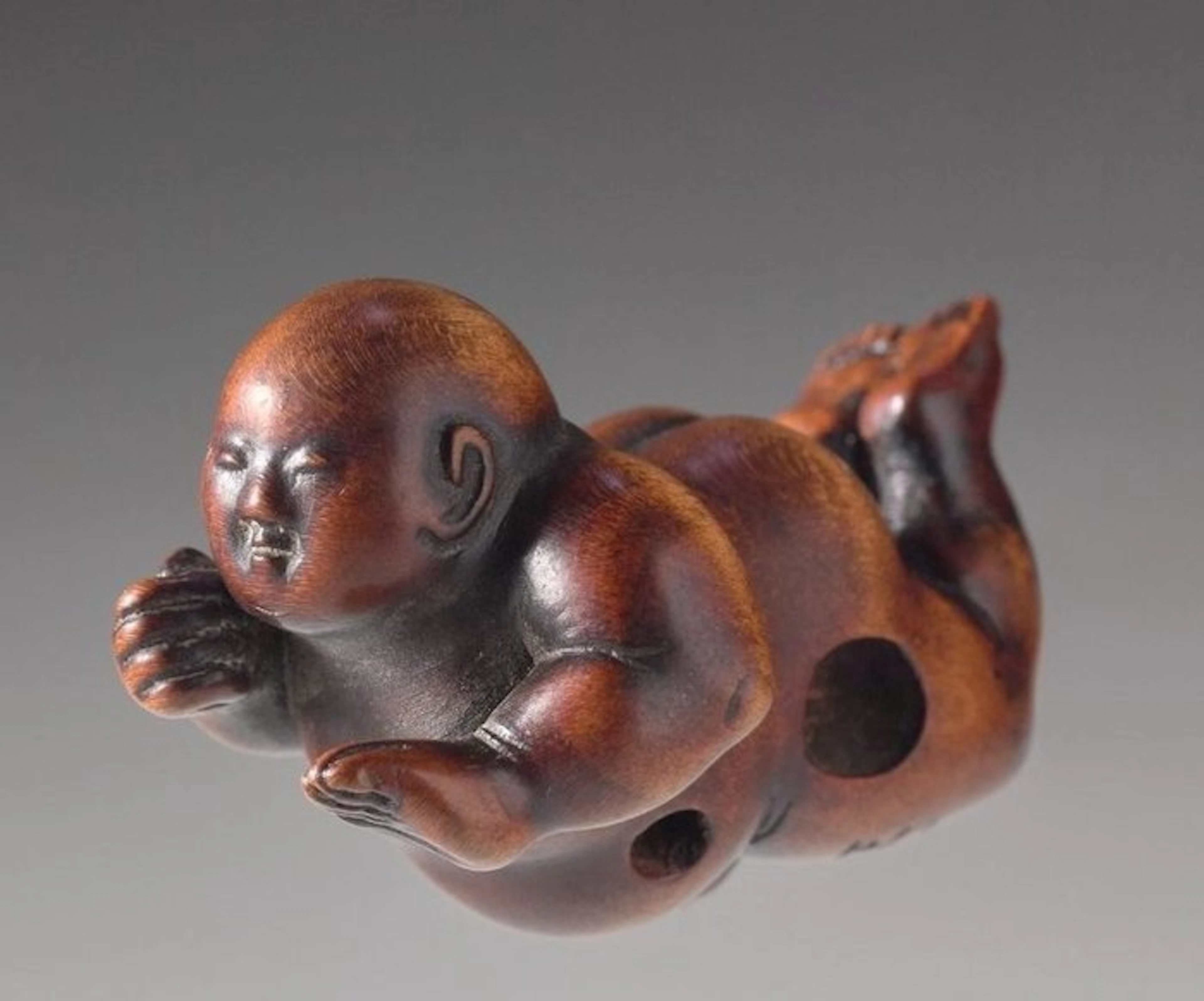 Japan Wood Wood netsuke depicting a child lying down, signed Masakazu. - 4.3 cm