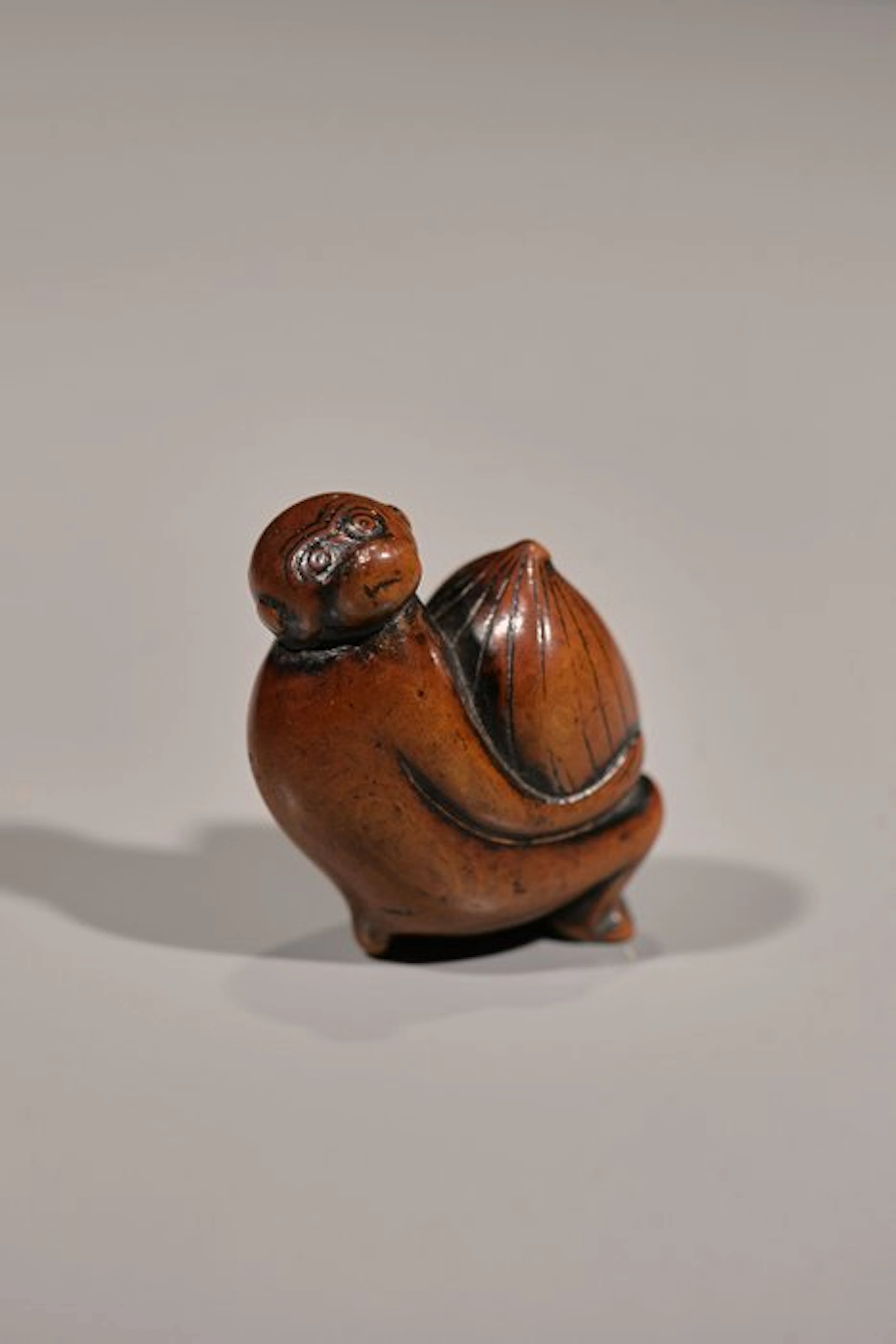 A soft, boxwood netsuke of a monkey with a bizarre expression