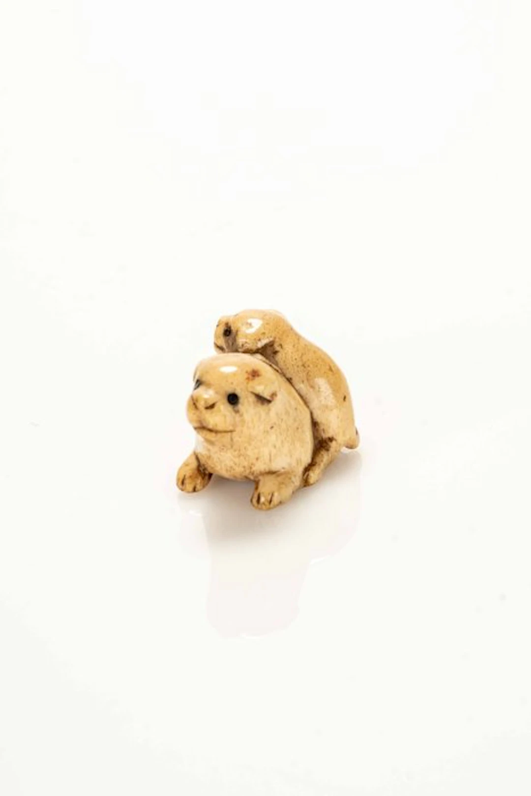 A fine and soft stag antler netsuke depicting two dog...