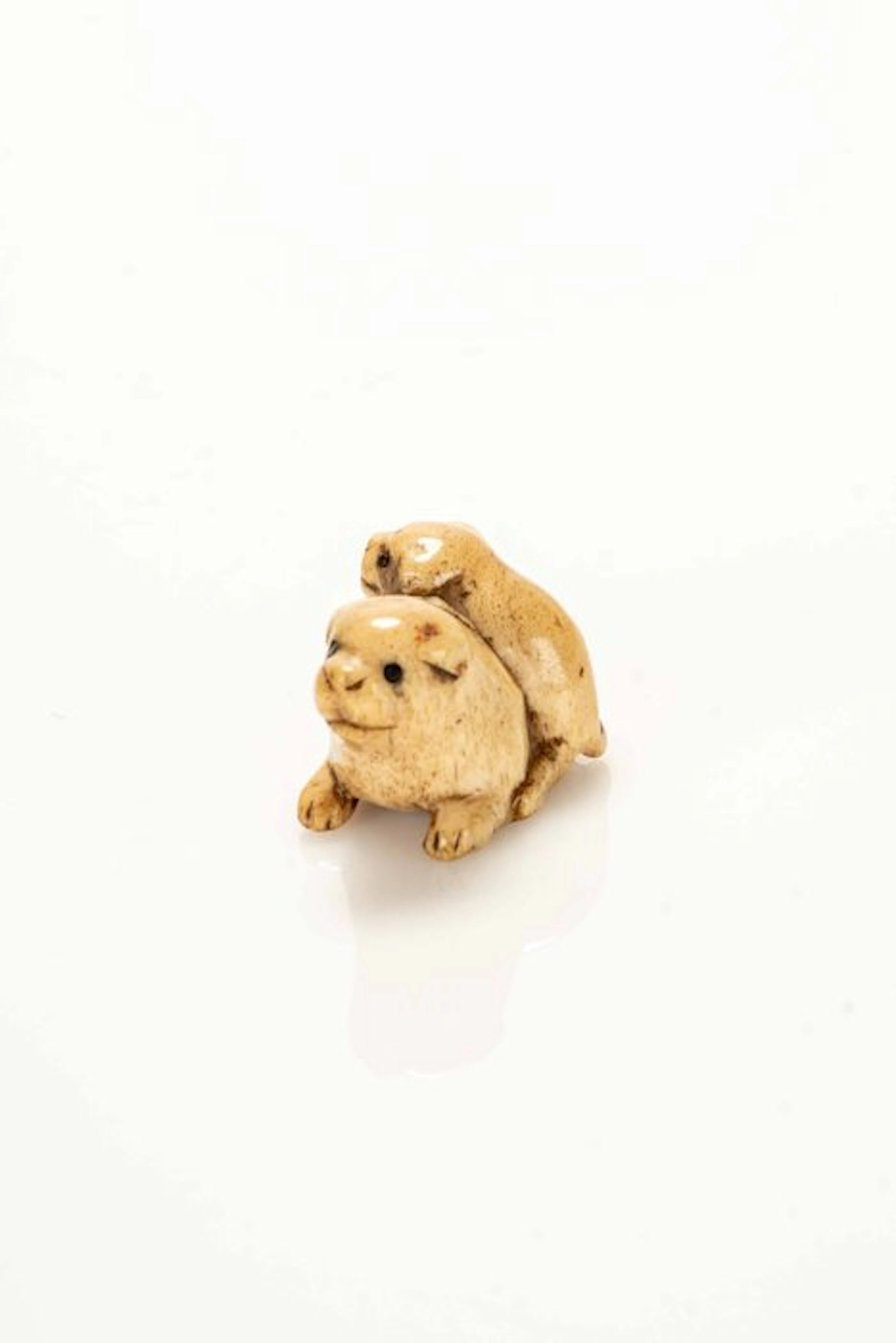 A fine and soft stag antler netsuke depicting two dog...