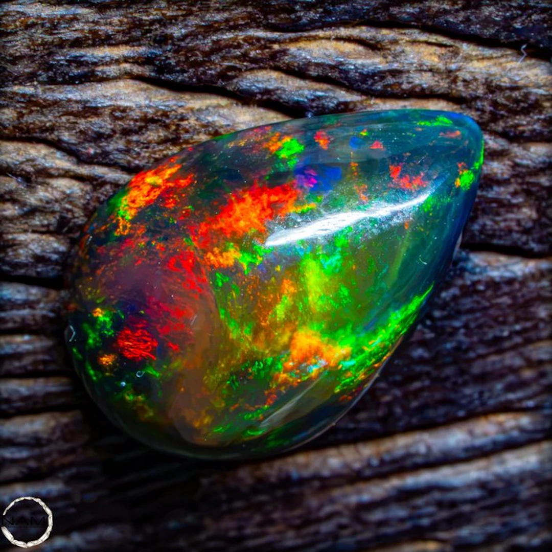 Black opal cabochon with an intense green-gold play of color. 1.8- 0.36 g