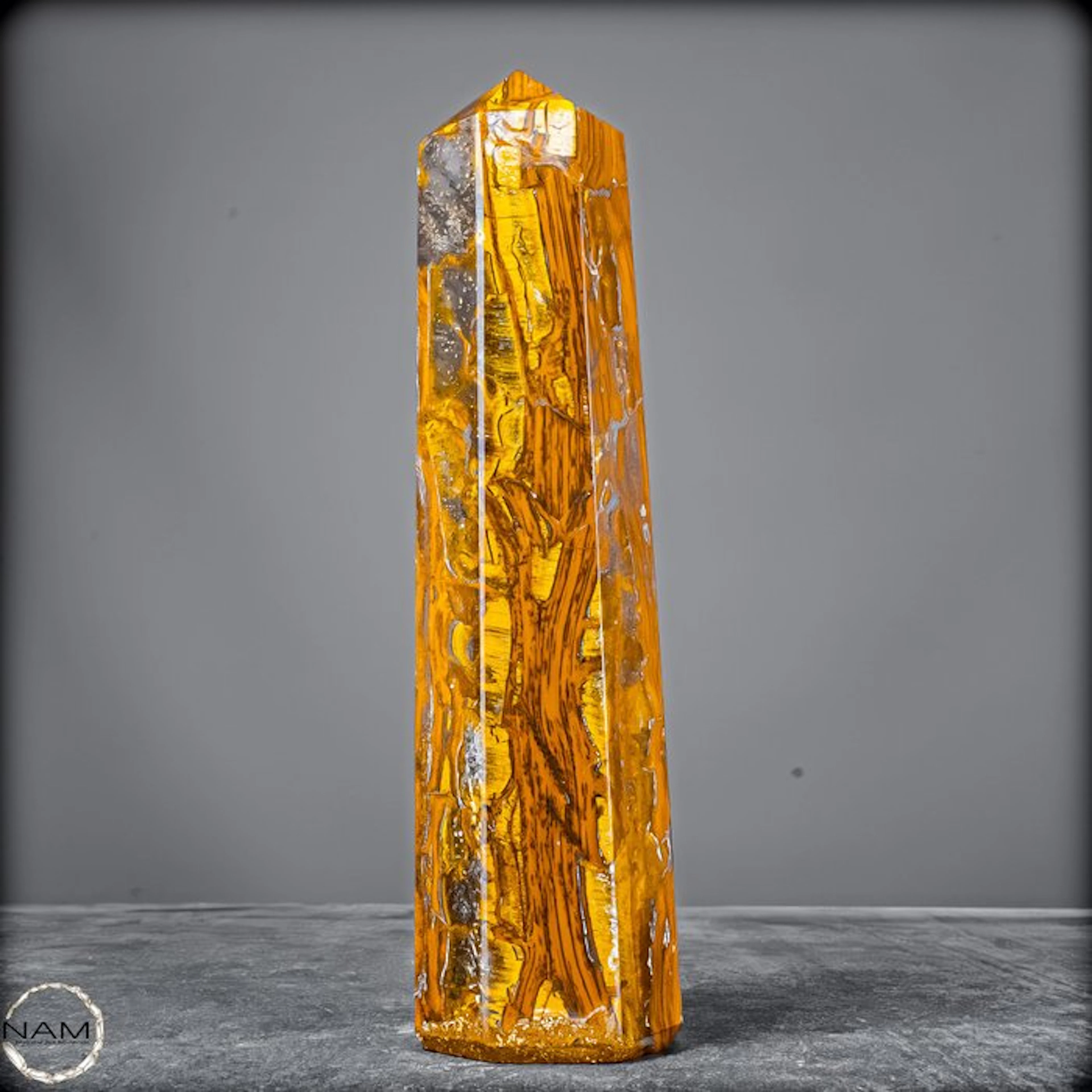 Natural tiger's-eye obelisk with a golden-brown silky texture.- 1089.66 g