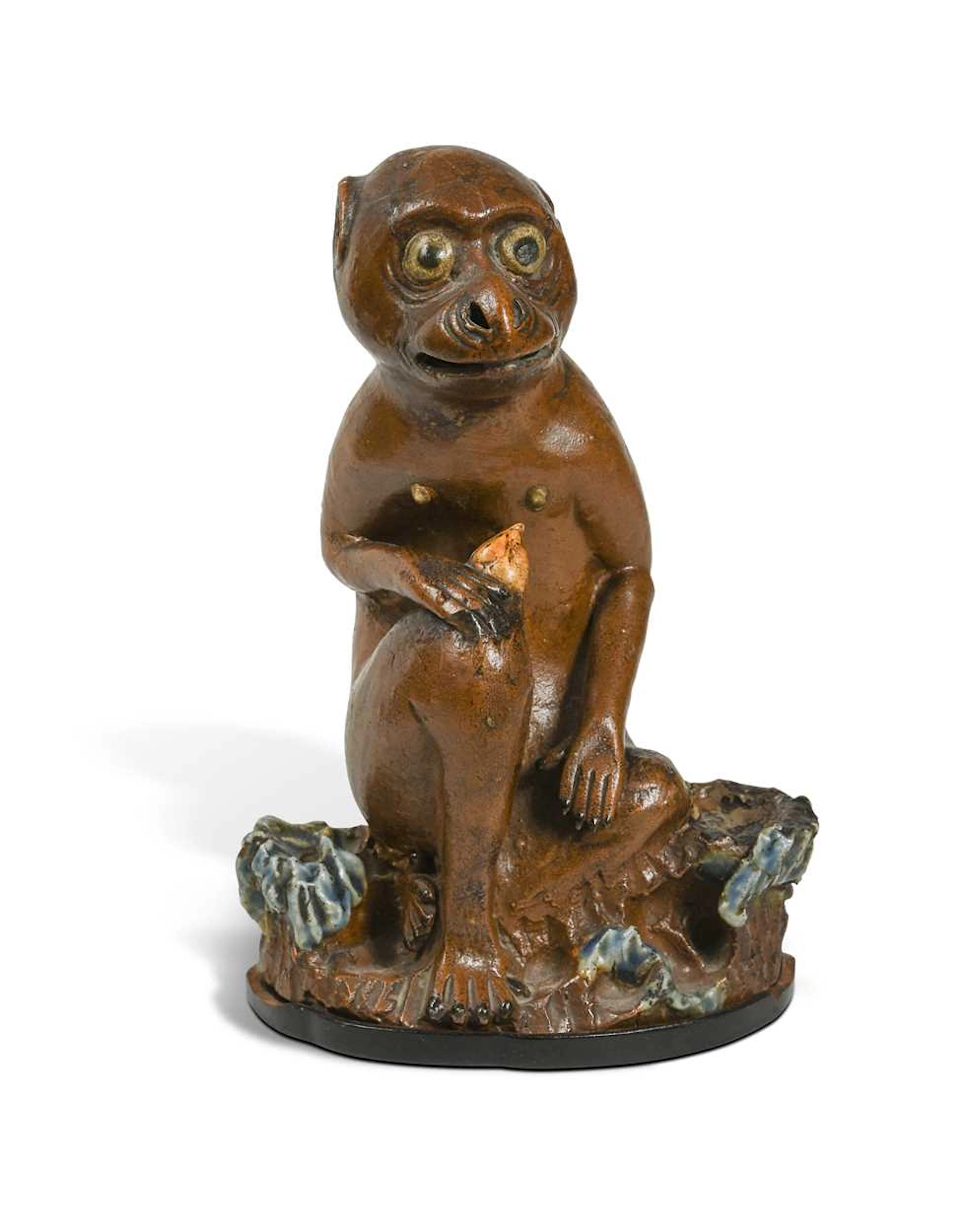 An Asian ceramic monkey, seated eating a nut, late 19th / early 20th century