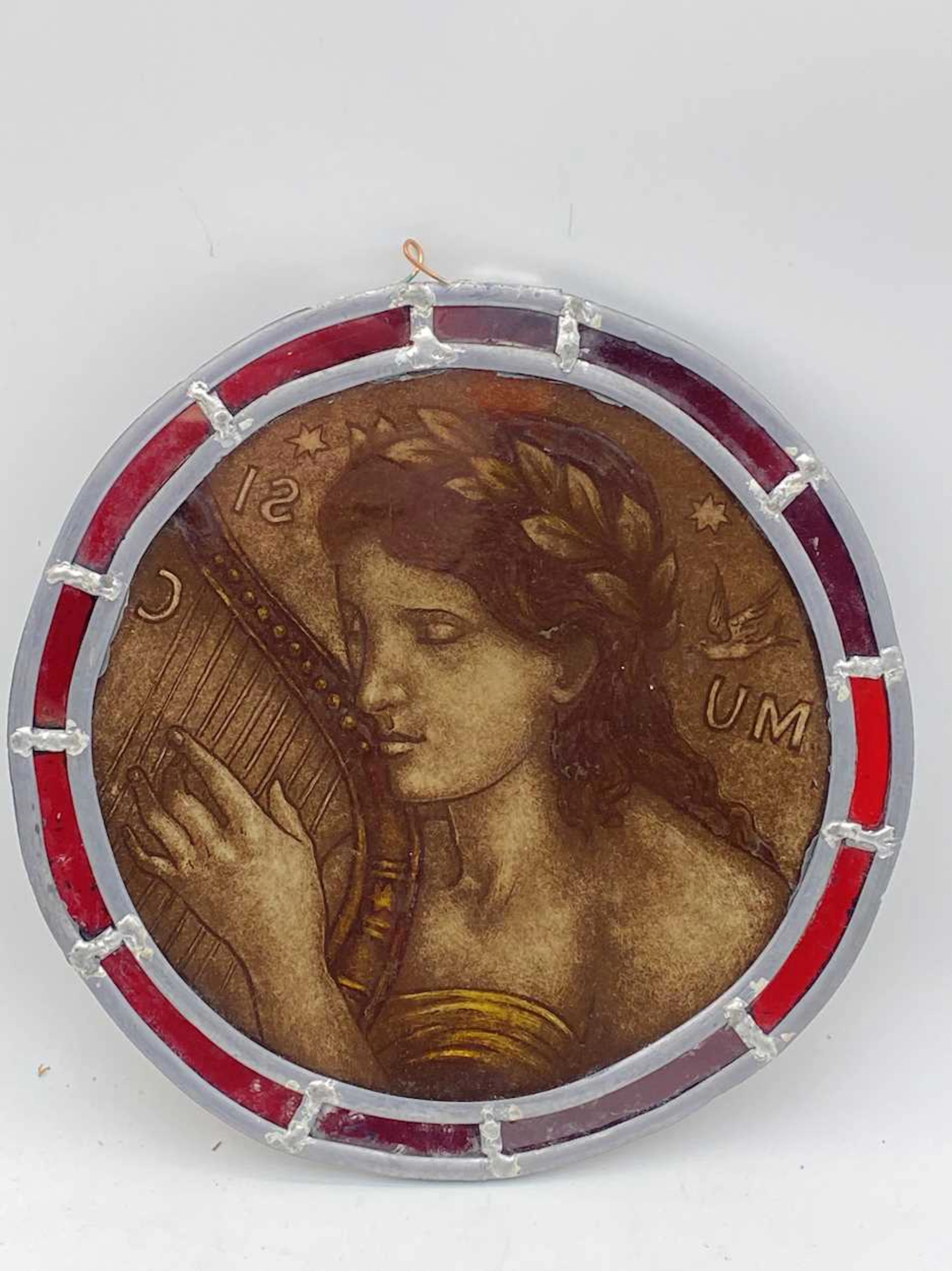 A pre-raphaelite style stained glass panel depicting a woman playing the harp