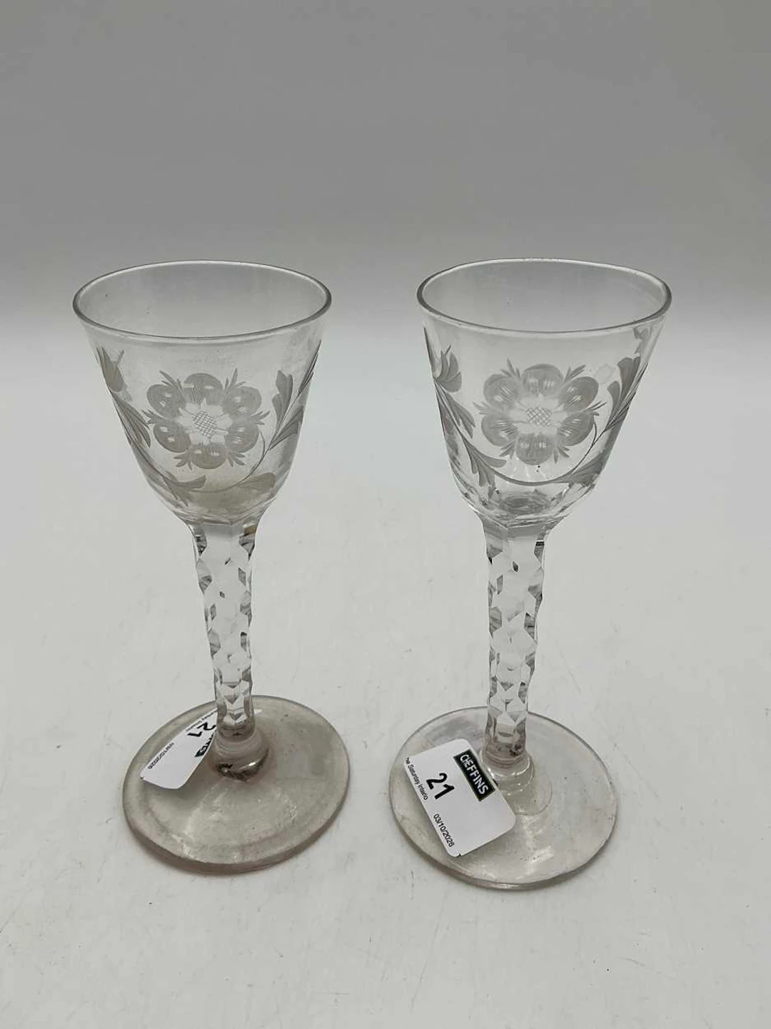 A pair of flower engraved wine glasses with facetted stems