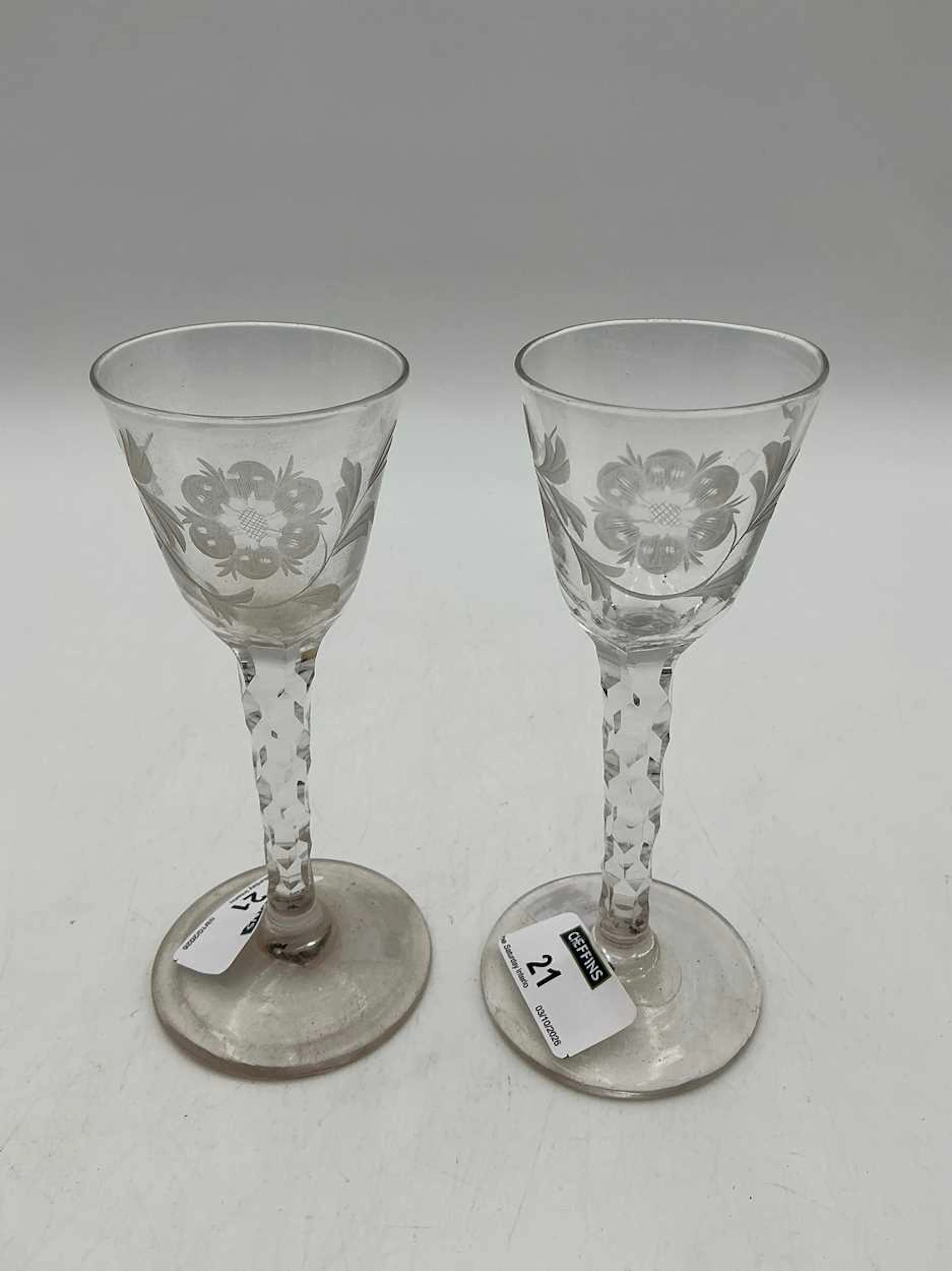 A pair of flower engraved wine glasses with facetted stems