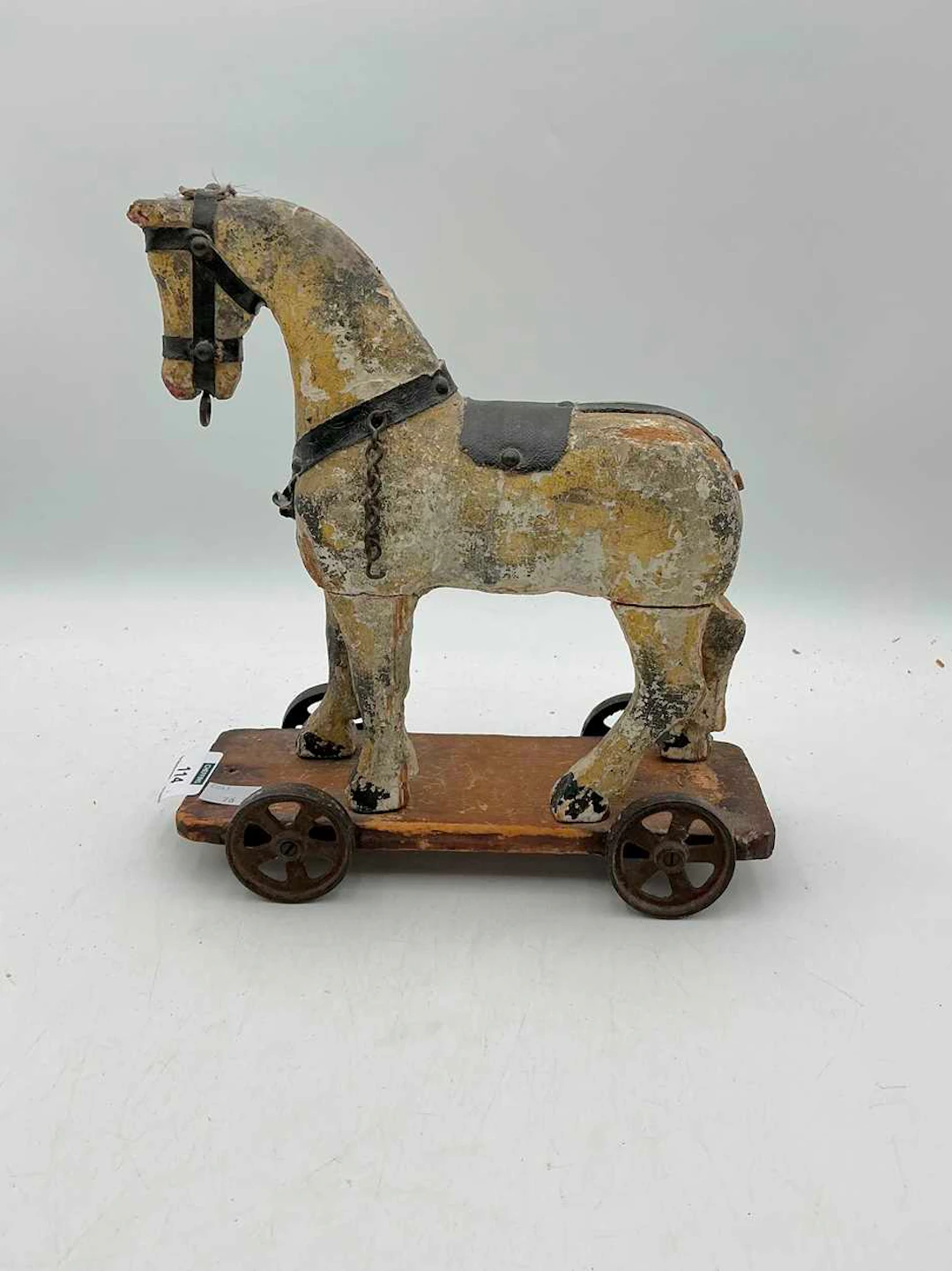 A naive painted and carved pull along toy horse with bridle and saddle