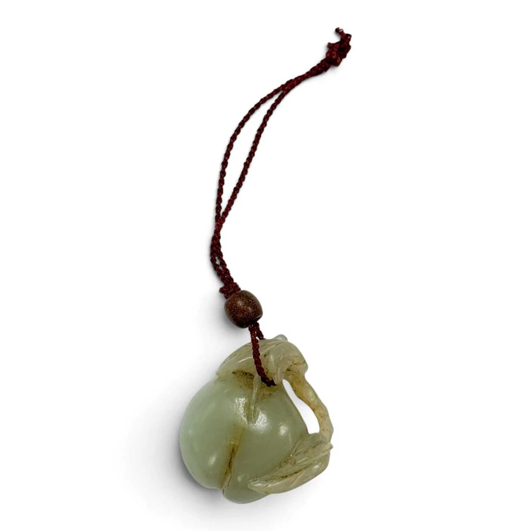 A Chinese carved celadon jade peach pendant, Qing Dynasty, 18th or 19th century