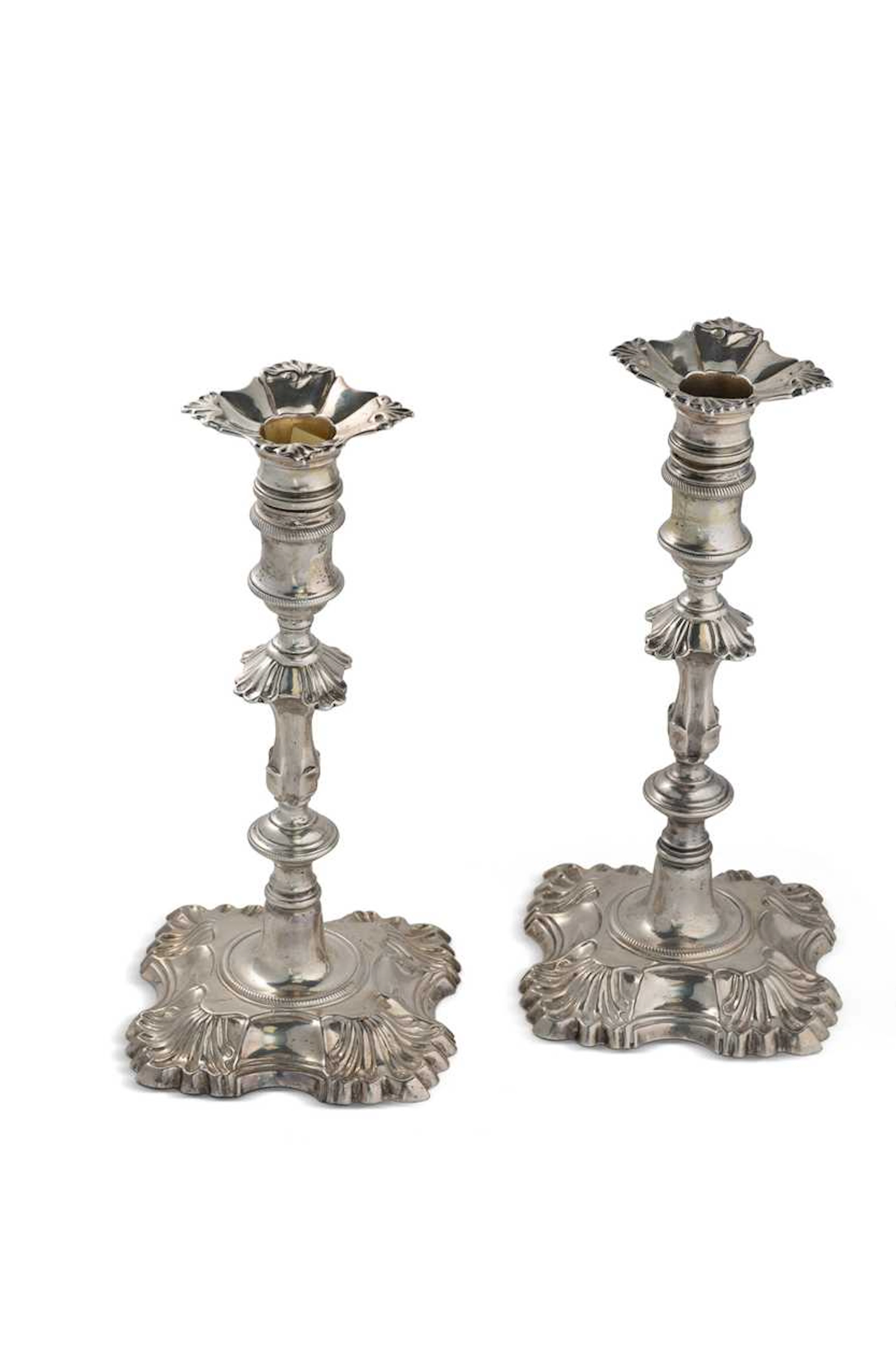 A matched pair of George II cast silver candlesticks