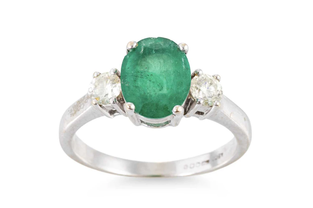 AN EMERALD AND DIAMOND THREE STONE RING
