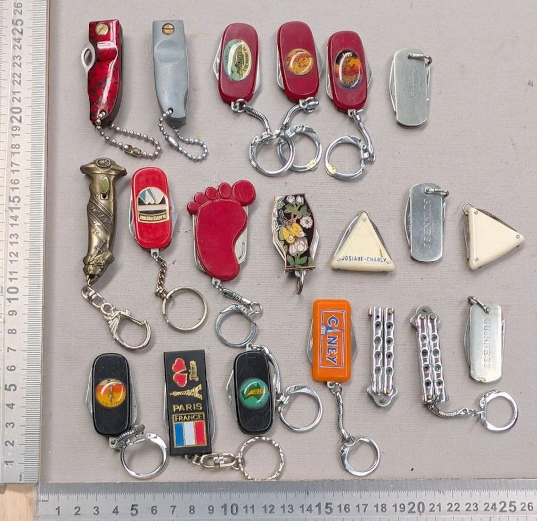 20 mini promotional and souvenir keychain pocket knives from the 1960s—see