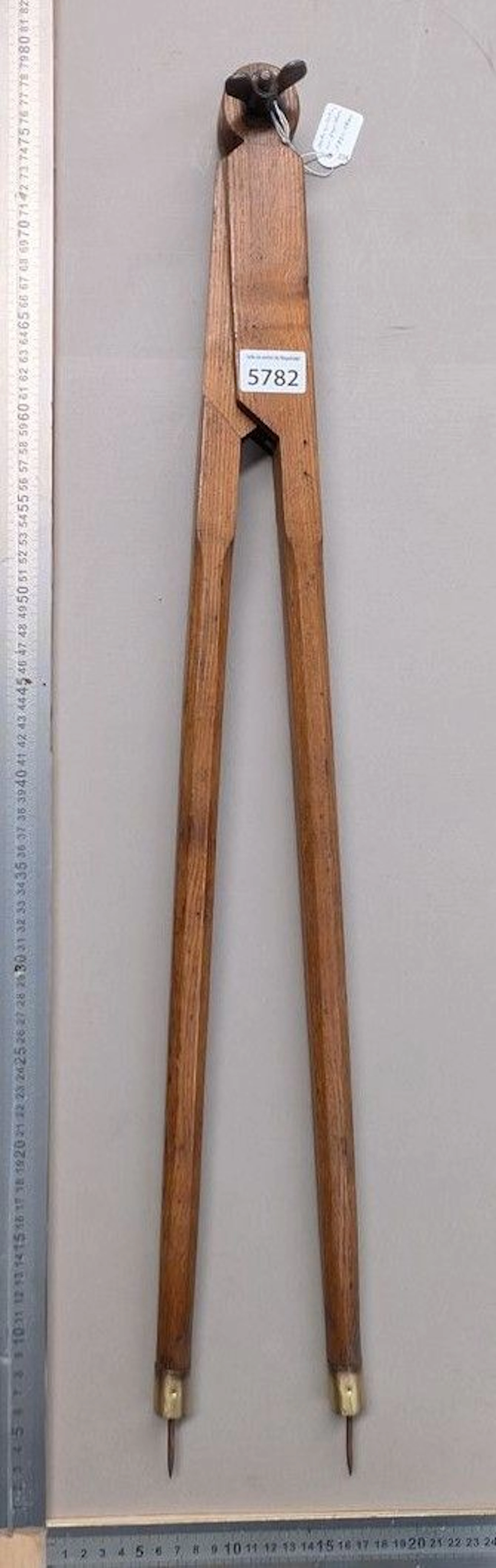 An old wooden compass with brass tips and a butterfly hinge screw—see