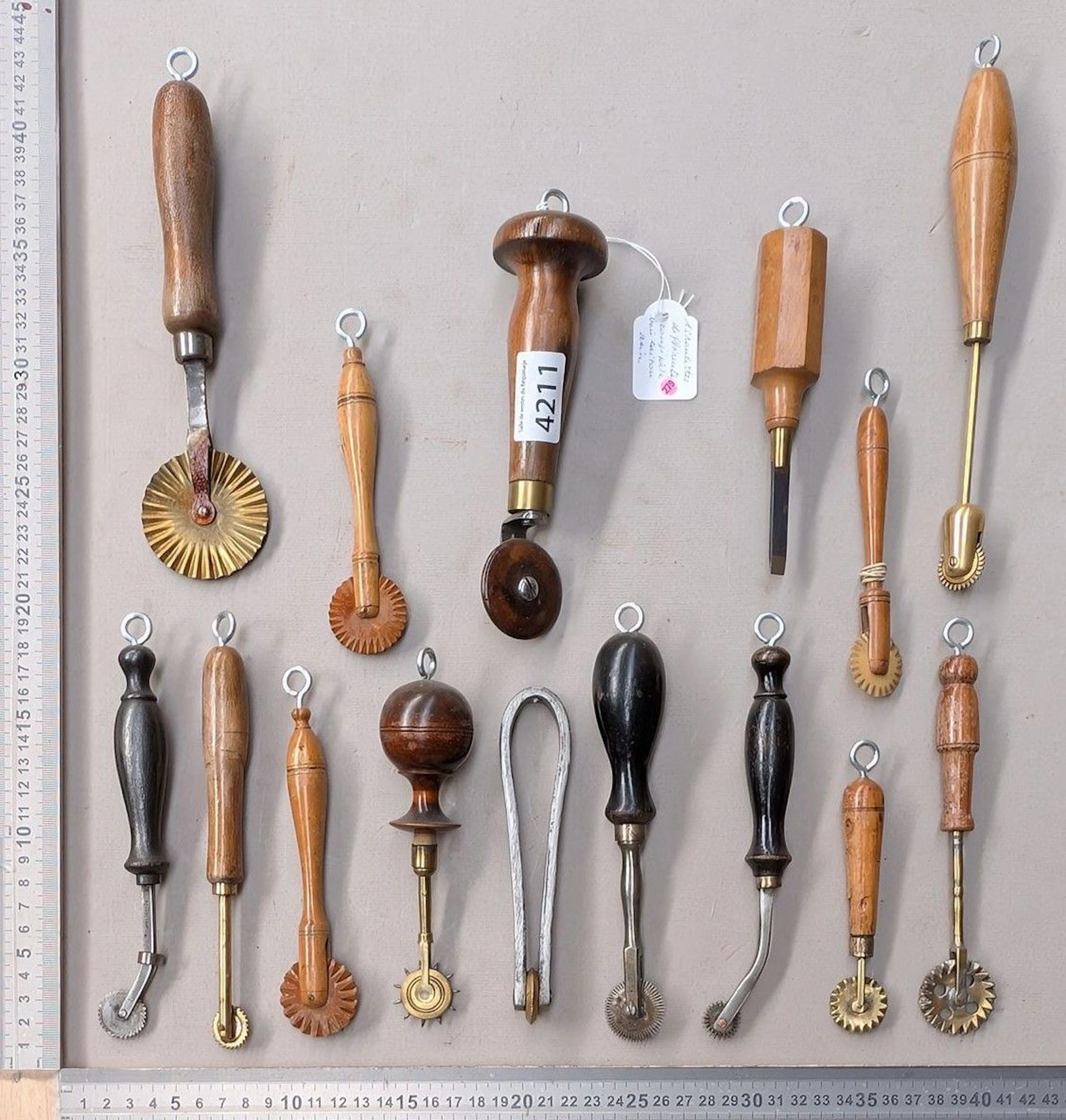 15 different dough cutters made of steel, brass, and wood on an oak