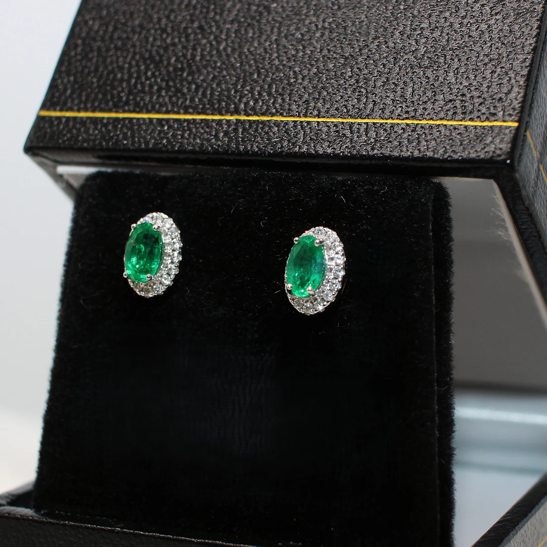 18K WHITE GOLD EMERALD AND DIAMOND STUDS.