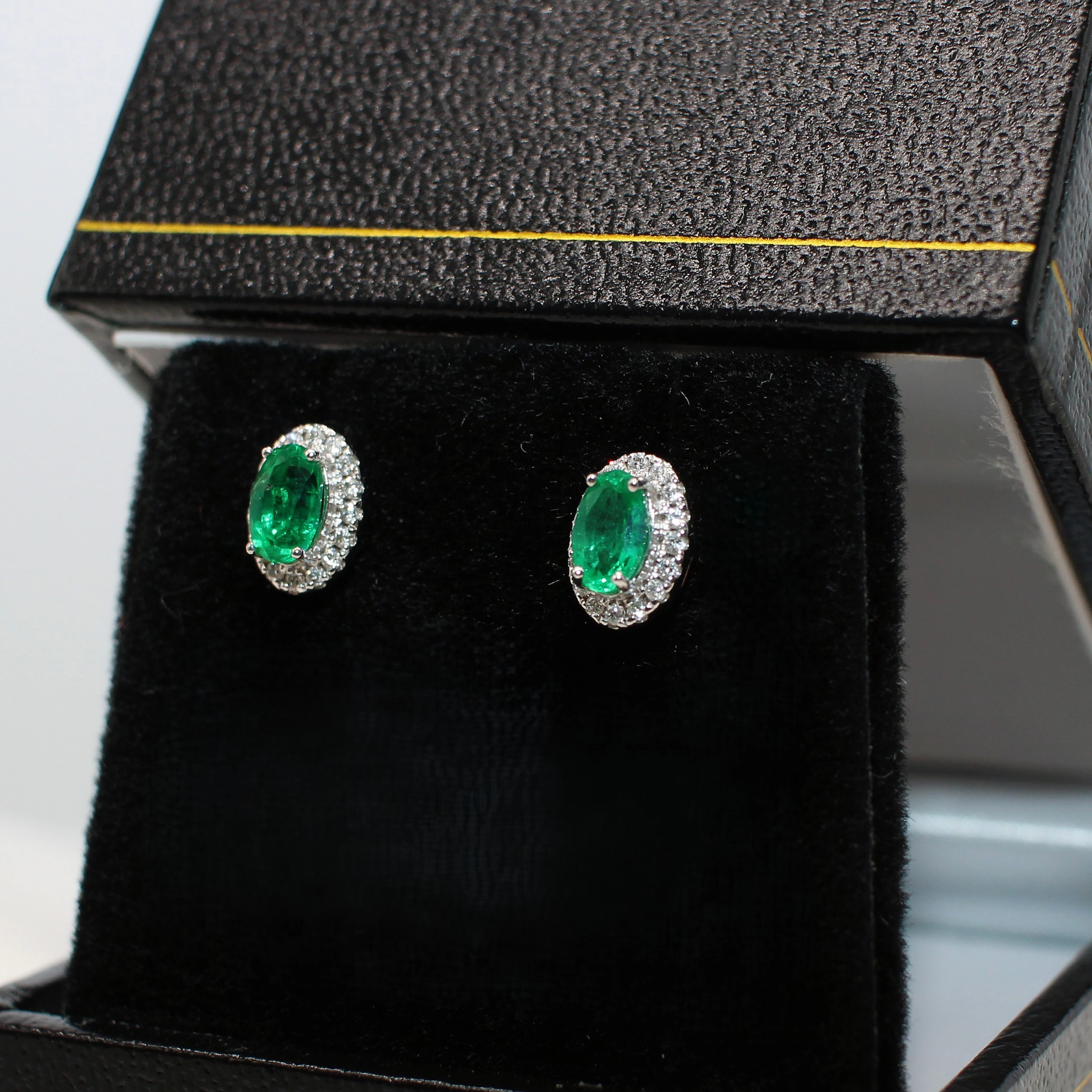 18K WHITE GOLD EMERALD AND DIAMOND STUDS.