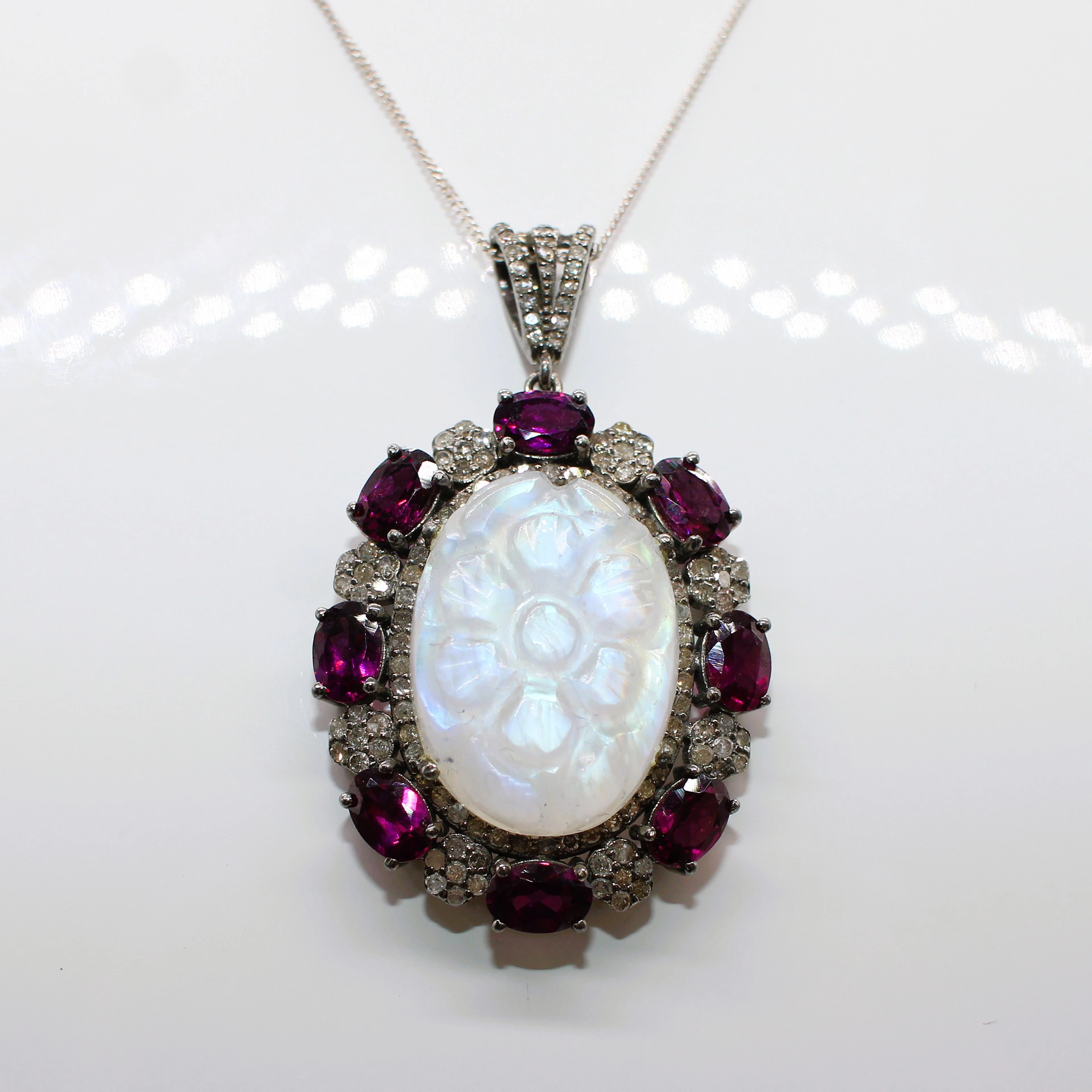 CARVED MOONSTONE , GARNET & DIAMOND PENDANT.