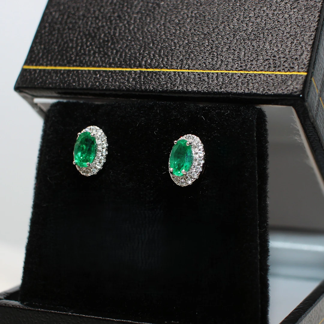 18K WHITE GOLD EMERALD AND DIAMOND STUDS.