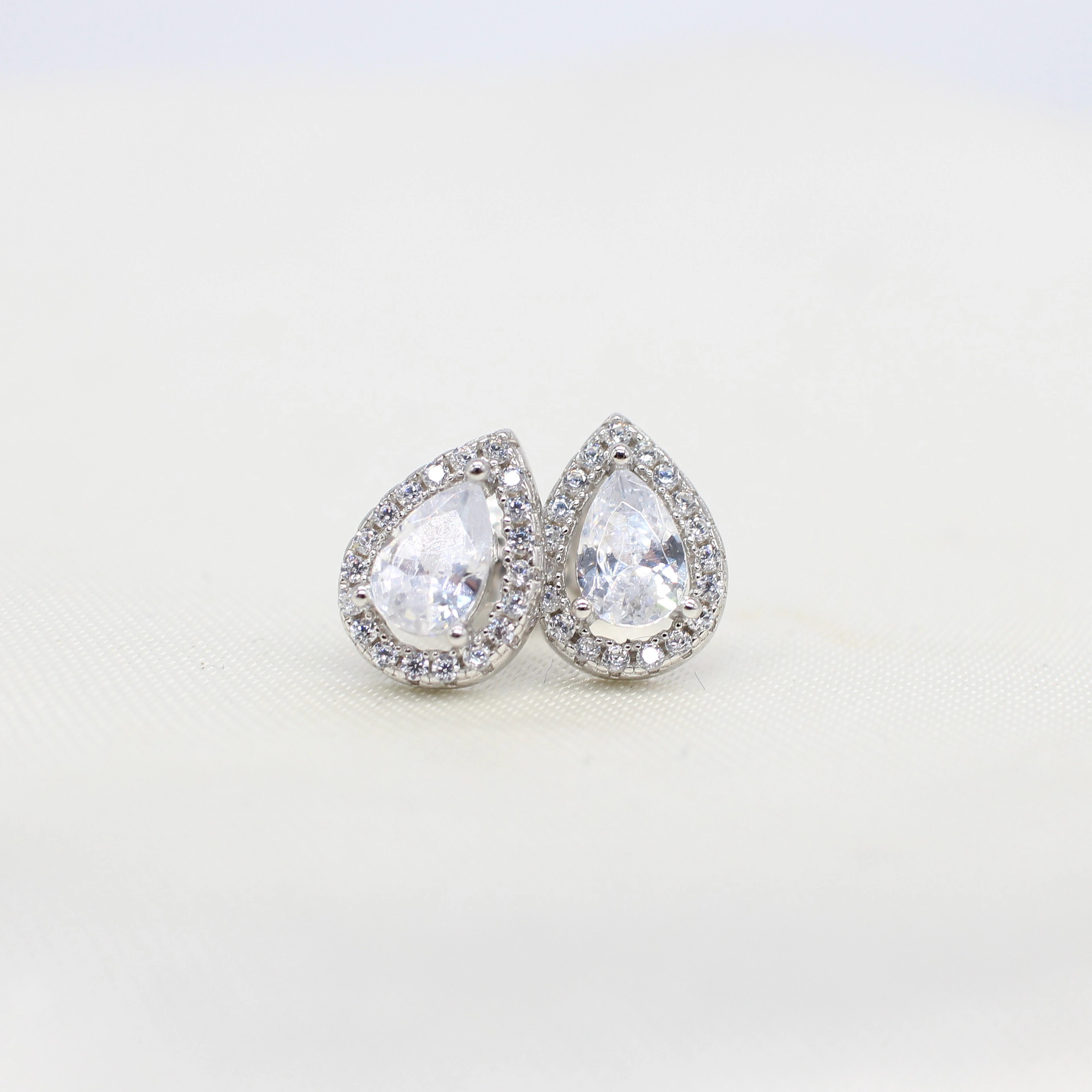SILVER PEAR SHAPED HALO STUDS.
