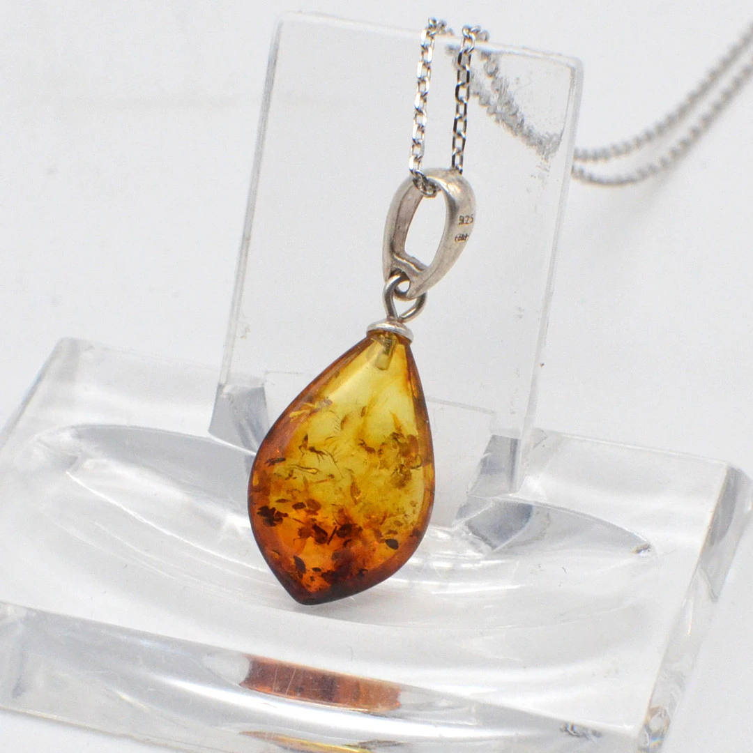 DESIGNERCOLLIER MIT EINEM BERNSTEIN-ANHÄNGER MIT BLATTEINSCHLÜSSEN