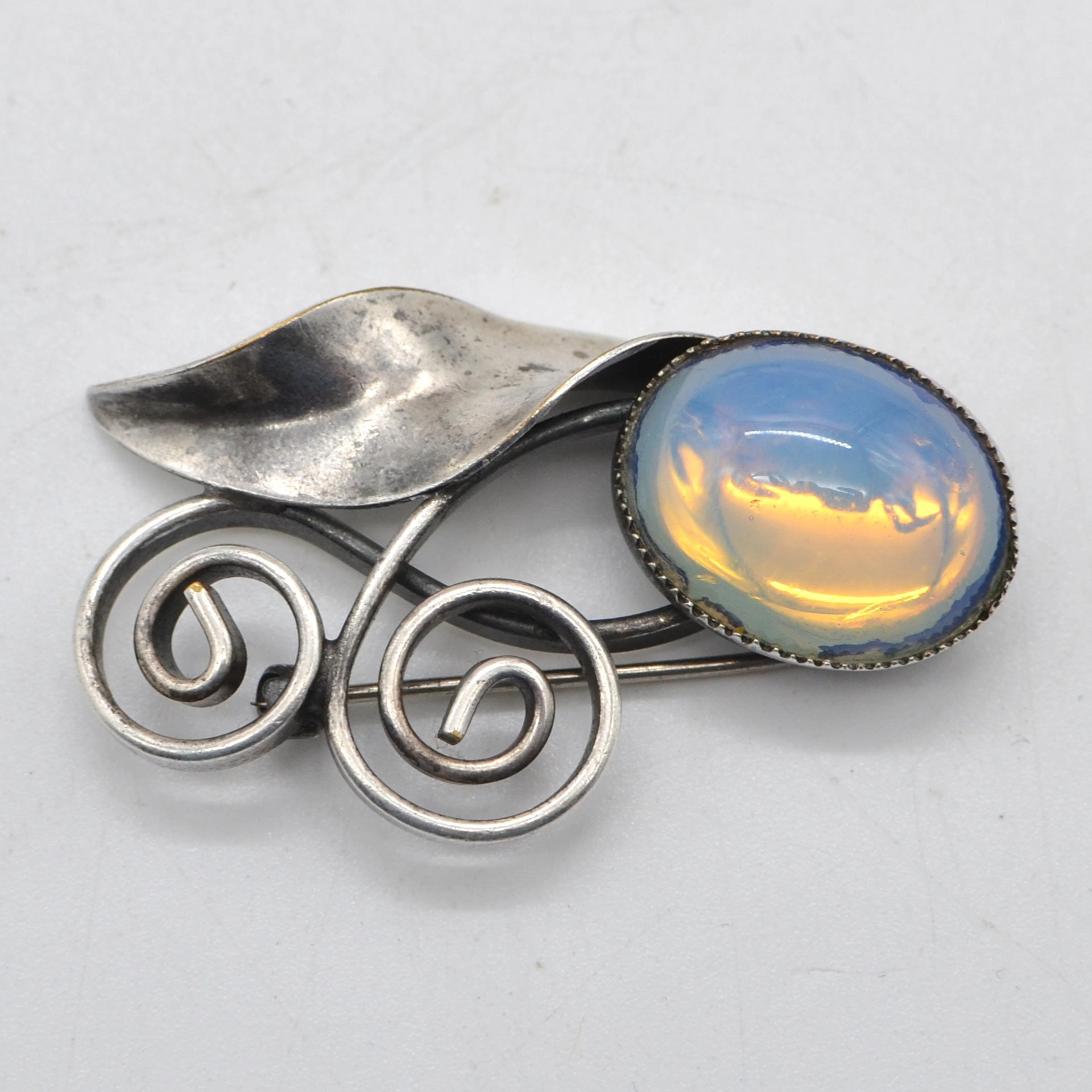 JUGENDSTILBROSCHE AUS SILBER (GEPRÜFT), OPALITH-CABOCHON, HANDGEMACHT, UM 1900.