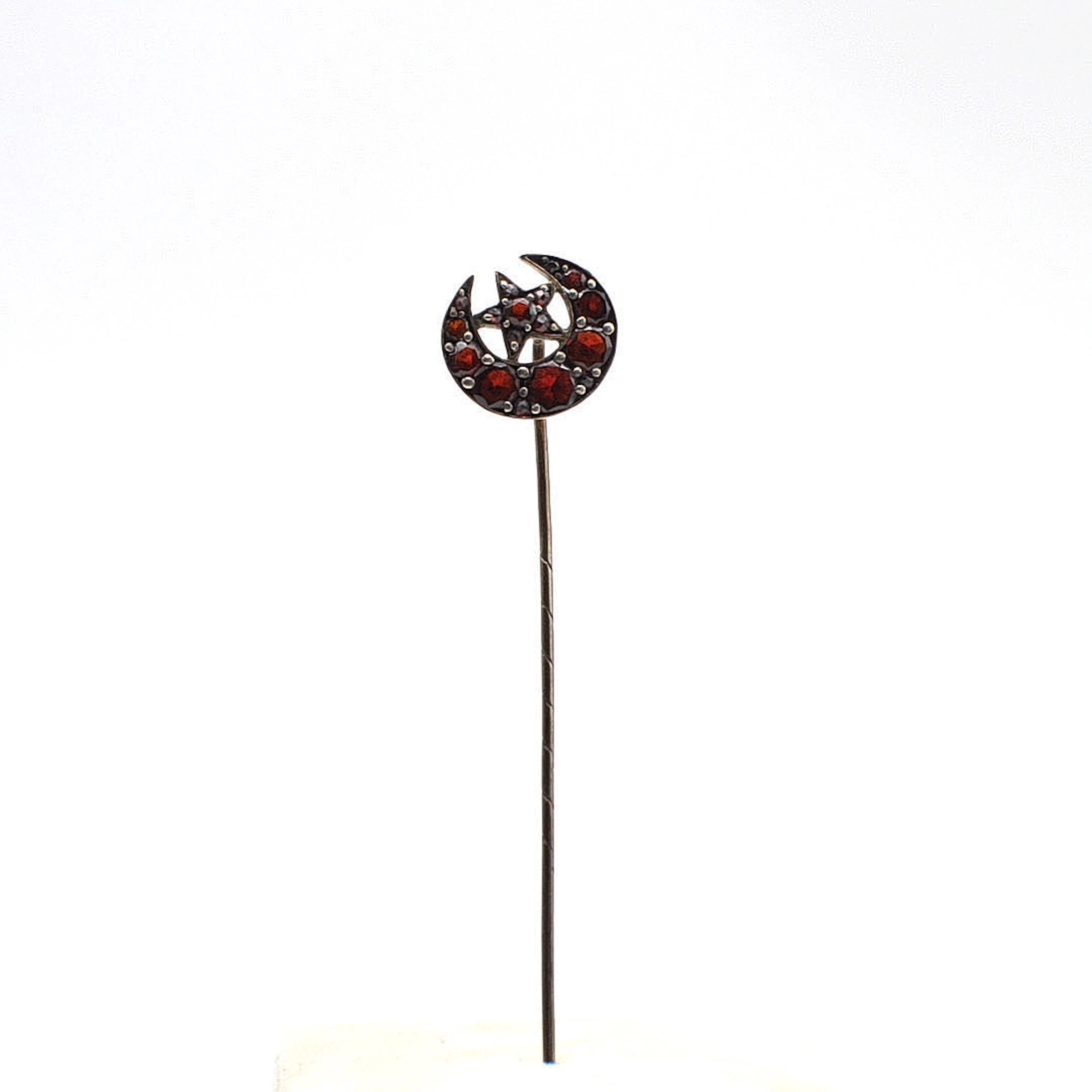 JUGENDSTIL KRAWATTENNADEL MIT GRANATEN, MOND UND STERN, UM 1900.